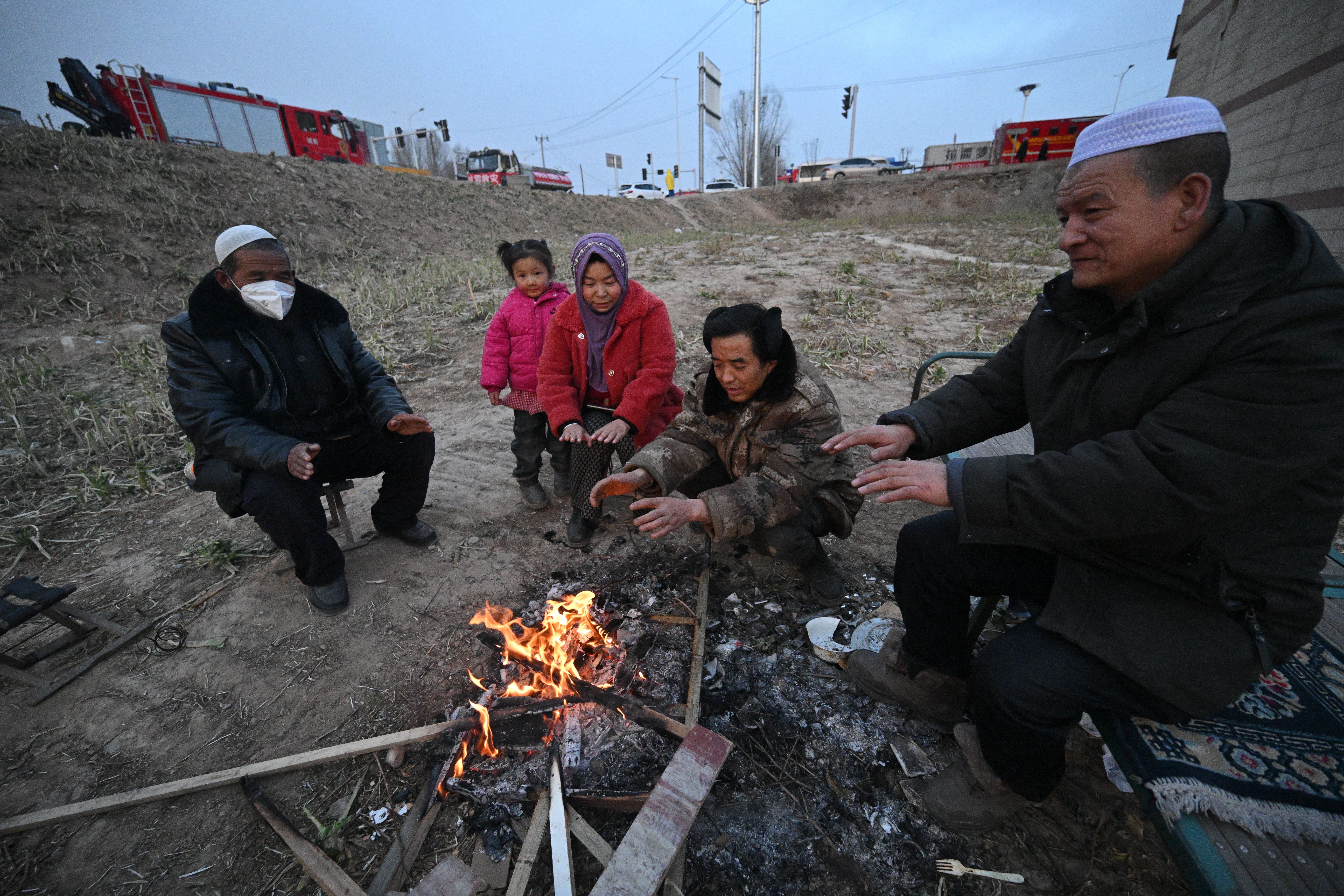 People gather next to a fire after an earthquake in Dahejia, Jishishan County in northwest China's Gansu