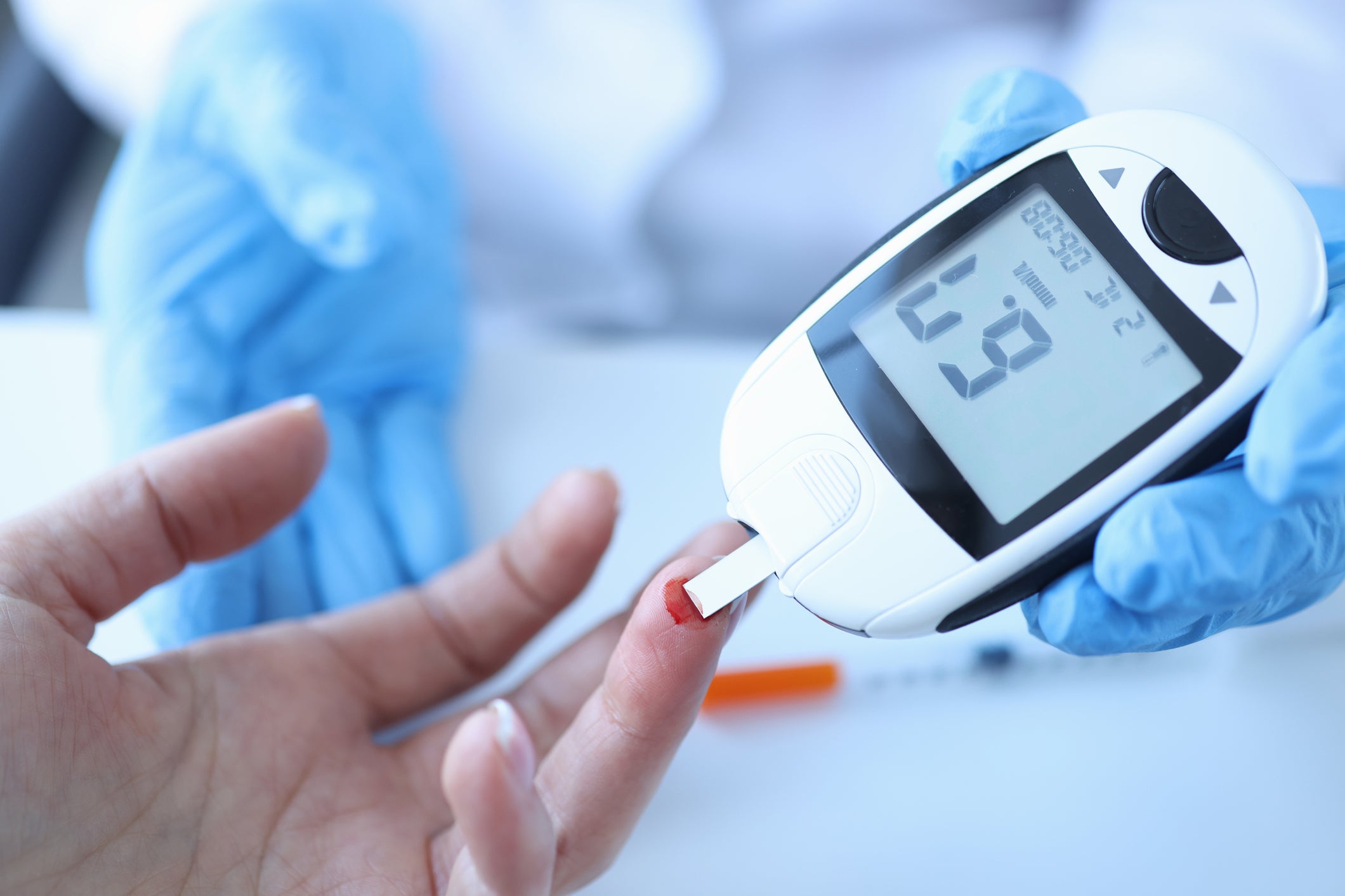 A doctor measuring patients blood glucose with a glucometer