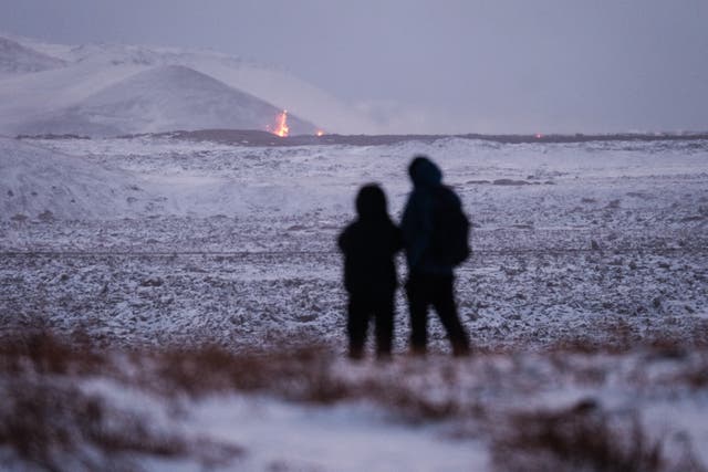<p>Locals watch from a safe distance as flames pour from the volcano </p>