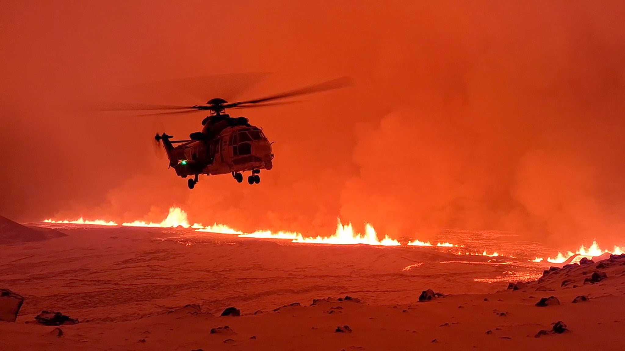 An Icelandic Coast Guard helicopter overflying a volcanic eruption on the Reykjanes peninsula, 3km north of Grindavik, western Iceland on 19 December