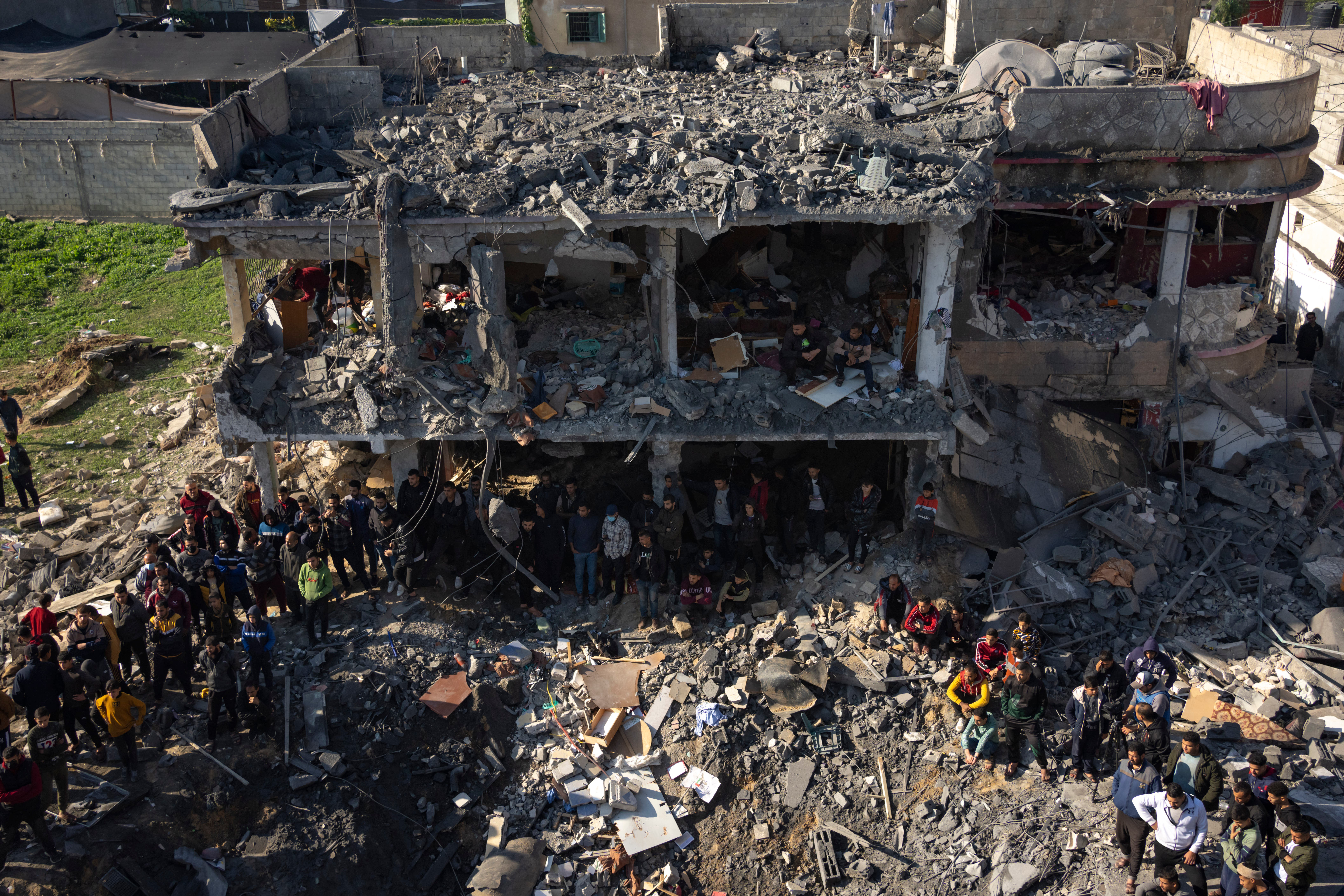 Palestinians search for bodies and survivors in the rubble of a residential building destroyed in an Israeli air strike, in Rafah (AP)