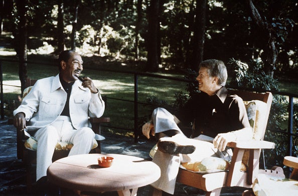 Former Egyptian president Anwar al-Sadat (L) and former president Jimmy Carter (R) chat before their meeting on 6 September 1978 at Camp David