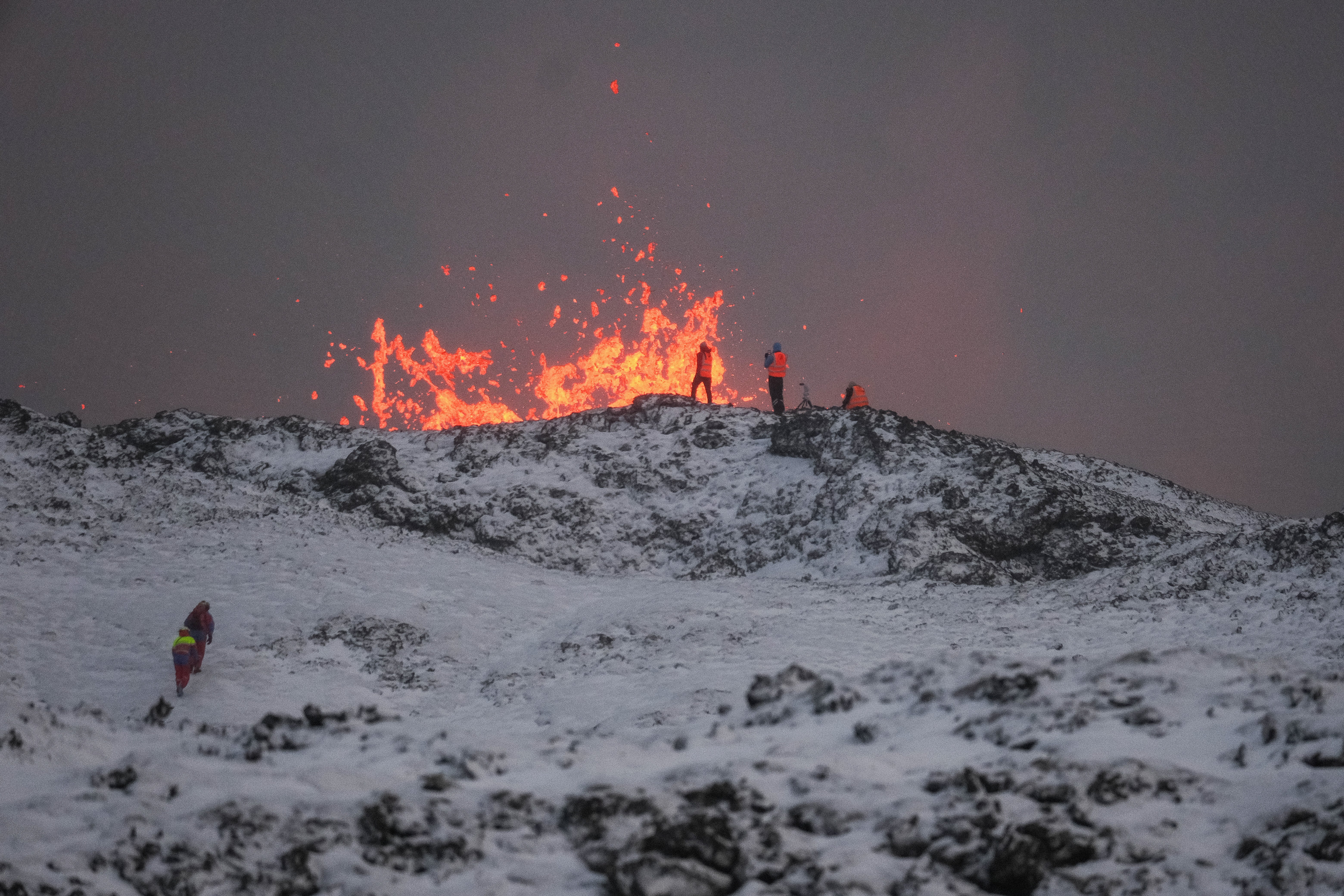 <p> A team of scientists works on the ridge of a volcanic fissure as lava spews during a volcanic eruption </p>