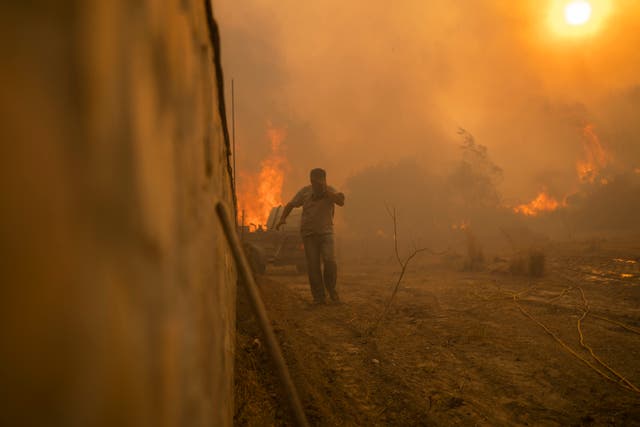 <p>A person runs to avoid the flames of a wildfire in Gennadi village, on the Aegean Sea island of Rhodes, in summer 2023 </p>