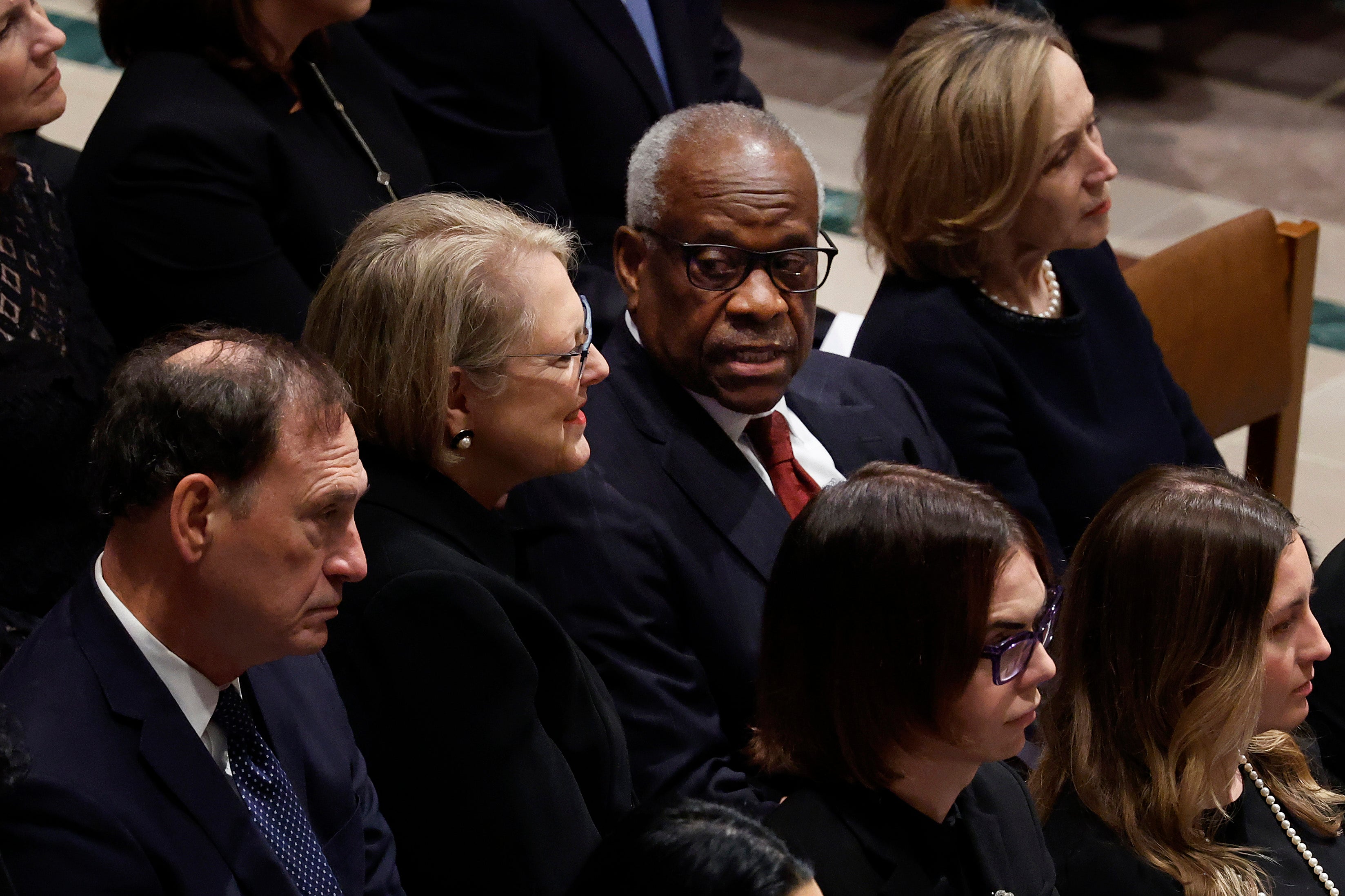US Supreme Court Justice Clarence Thomas, centre, speaks with his wife Ginni Thomas, seated next to Justice Samuel Alito, at Sandra Day O’Connor’s funeral on 19 December.