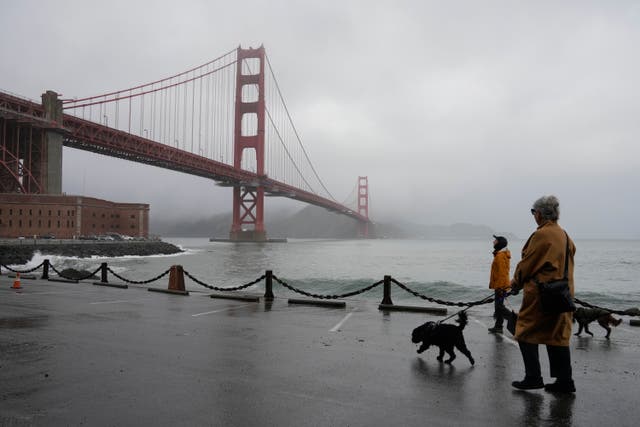 <p>People walk their dogs during a break between rain showers near the Golden Gate Bridge and Fort Point in San Francisco, 19 December 2023</p>