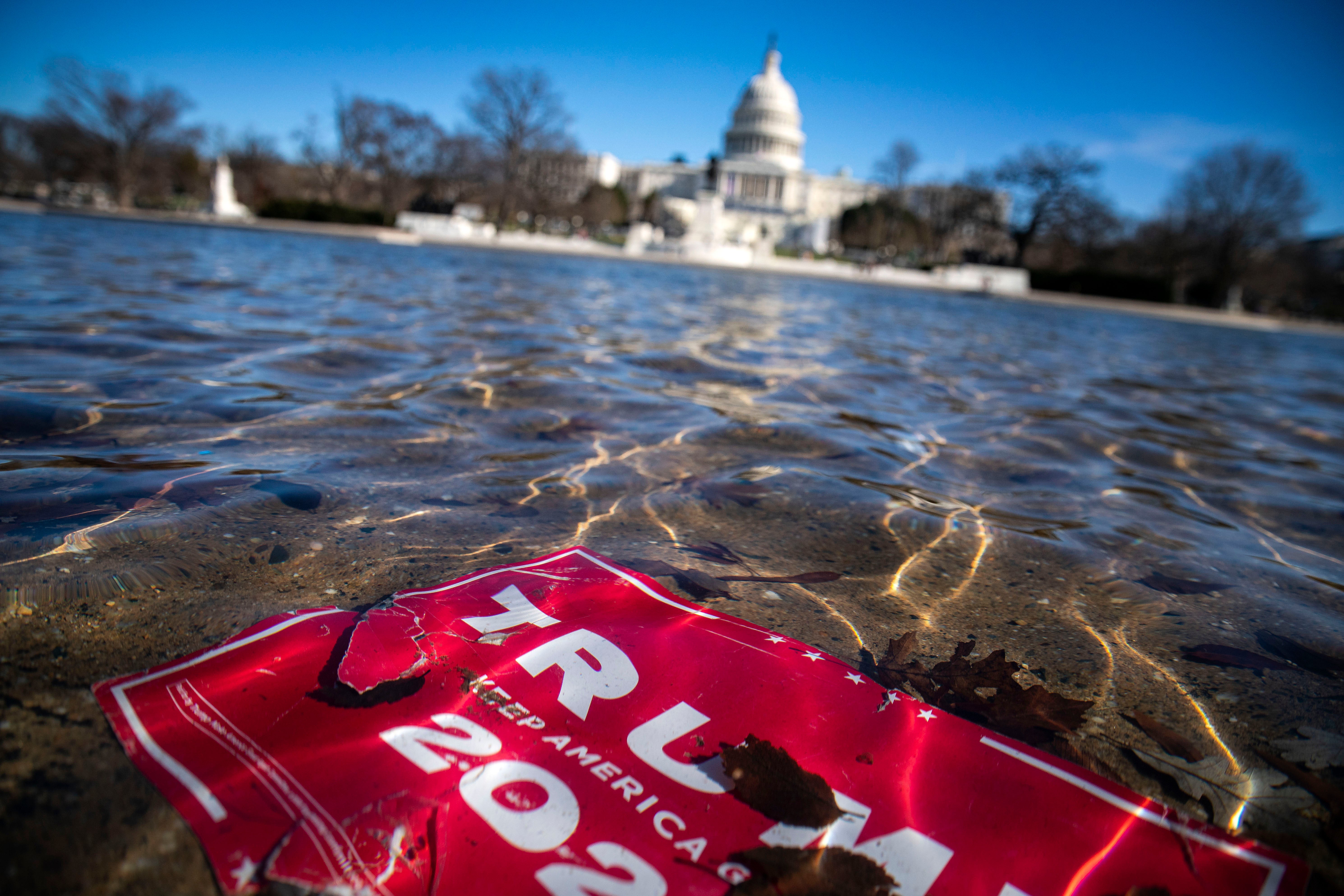A campaign sign for U.S. President Donald Trump lies beneath water in the Capitol Reflecting Pool on Capitol Hill on 9 January 2021 in Washington DC
