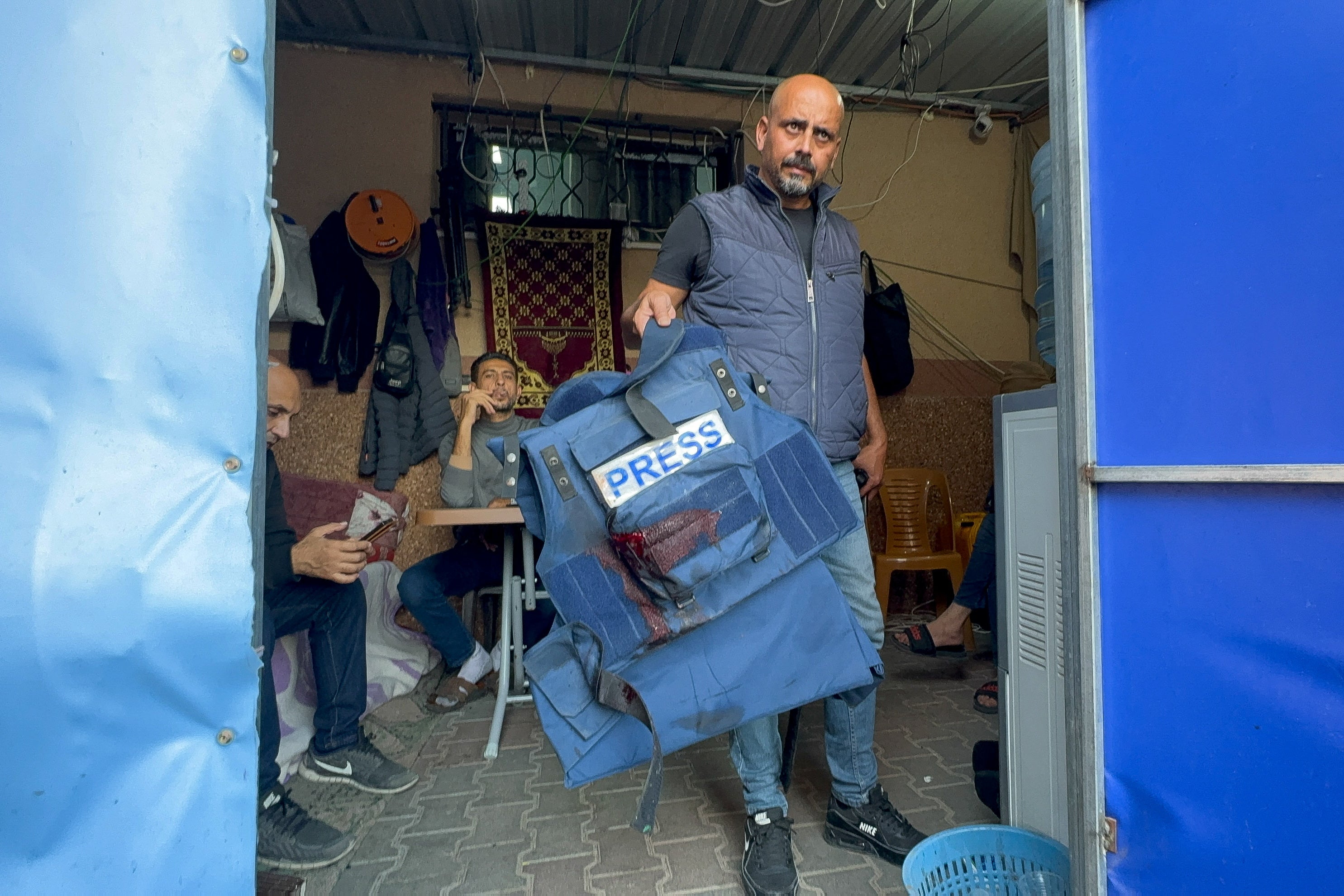 <p>A man holds the flak jacket belonging to the wounded Al Jazeera journalist Wael al-Dahdouh, in Khan Younis</p>