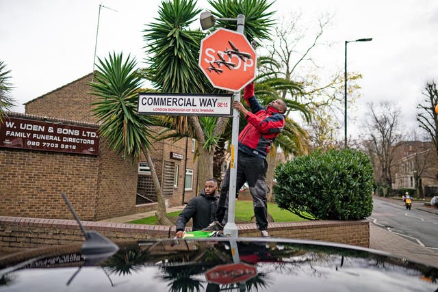 A man removes a piece of art work by Banksy (Aaron Chown/PA)