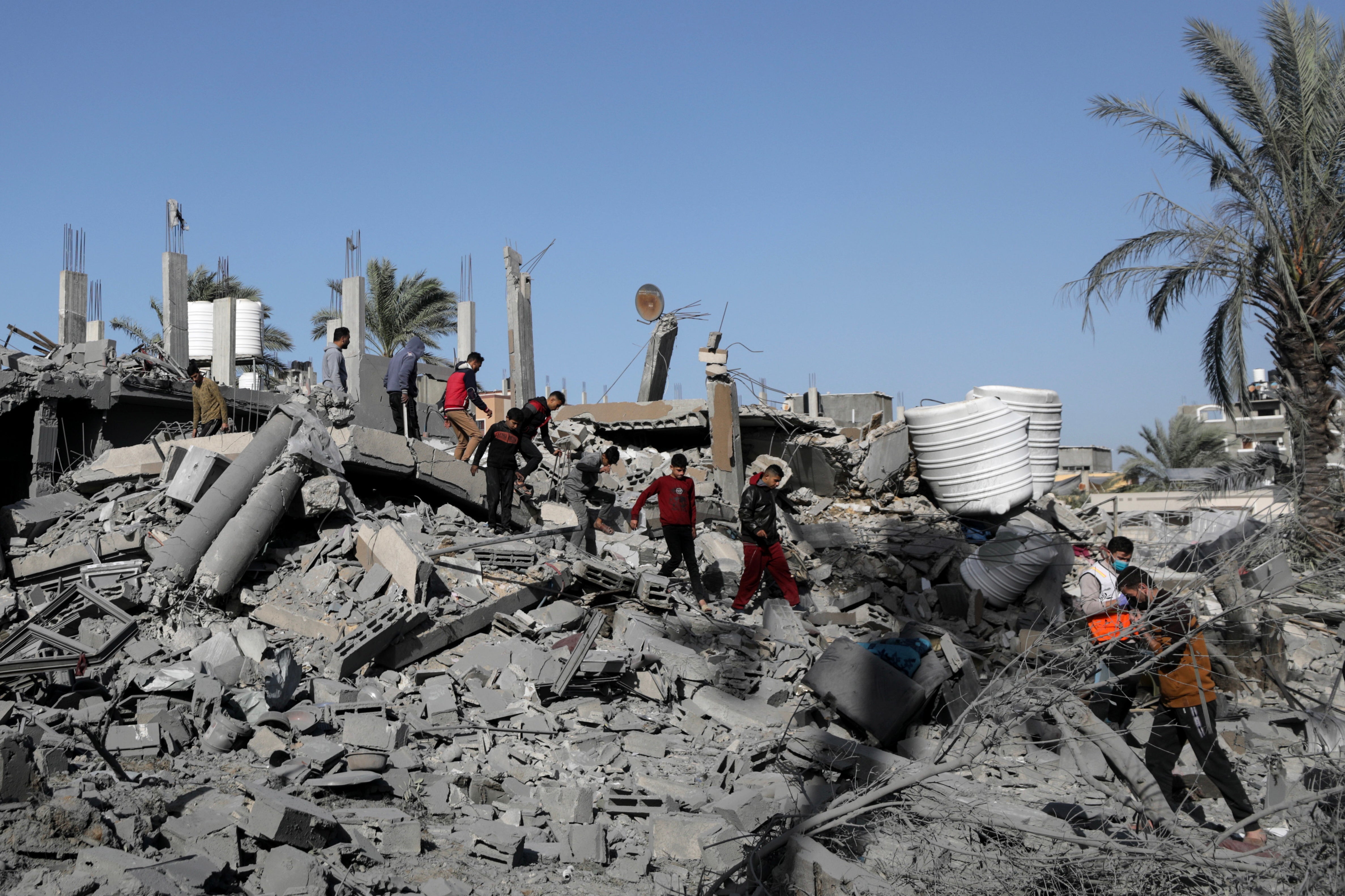 Palestinians walk among rubble of buildings in Al-Nuseirat refugee camp in Gaza on 22 December after it was bombed by Israeli airstrikes