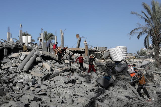 <p>Palestinians walk among rubble of buildings in Al-Nuseirat refugee camp in Gaza on 22 December after it was bombed by Israeli airstrikes.</p>