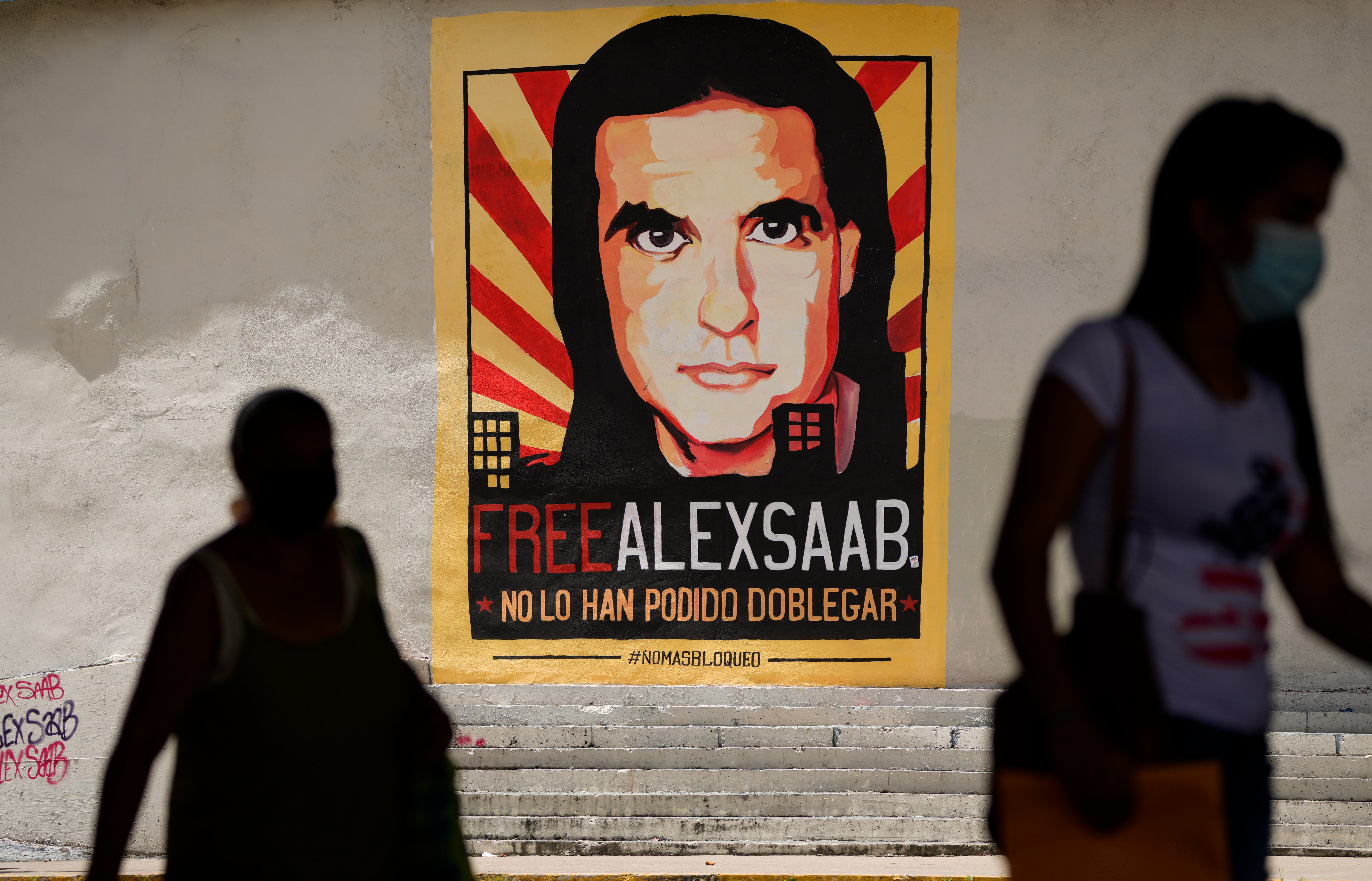 Pedestrians walk near a poster asking for the freedom of Colombian businessman and Venezuelan special envoy Alex Saab, in Caracas, Venezuela, 9 September 2021.