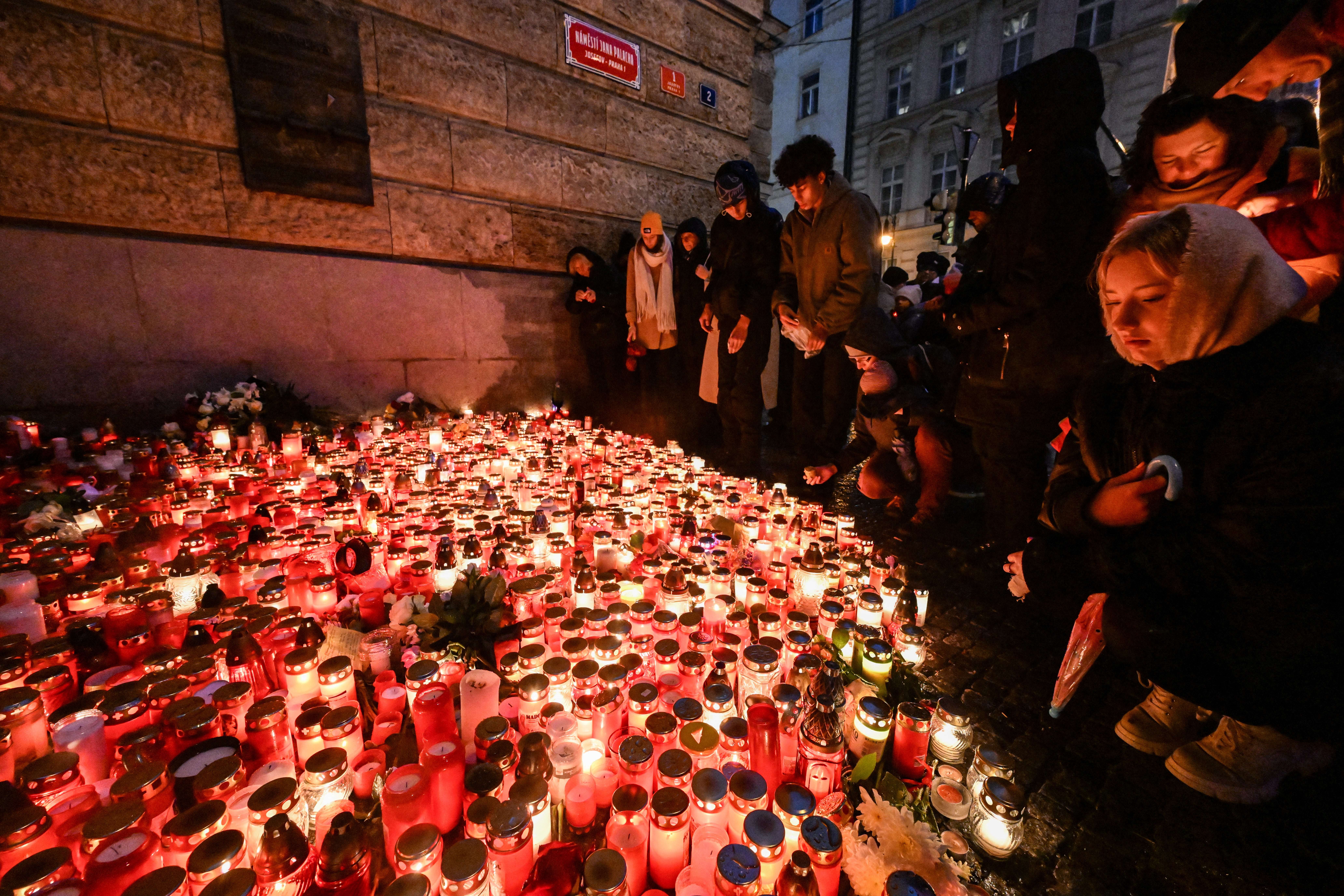 People place candles and flowers at a makeshift memorial for the victims of the Charles University shooting outside the Charles University in central Prague on Saturday