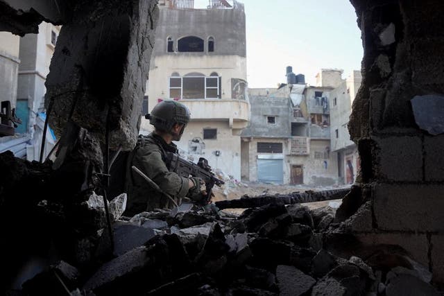 <p>An Israeli solider stands next to a destroyed building in Khan Younis, southern Gaza</p>