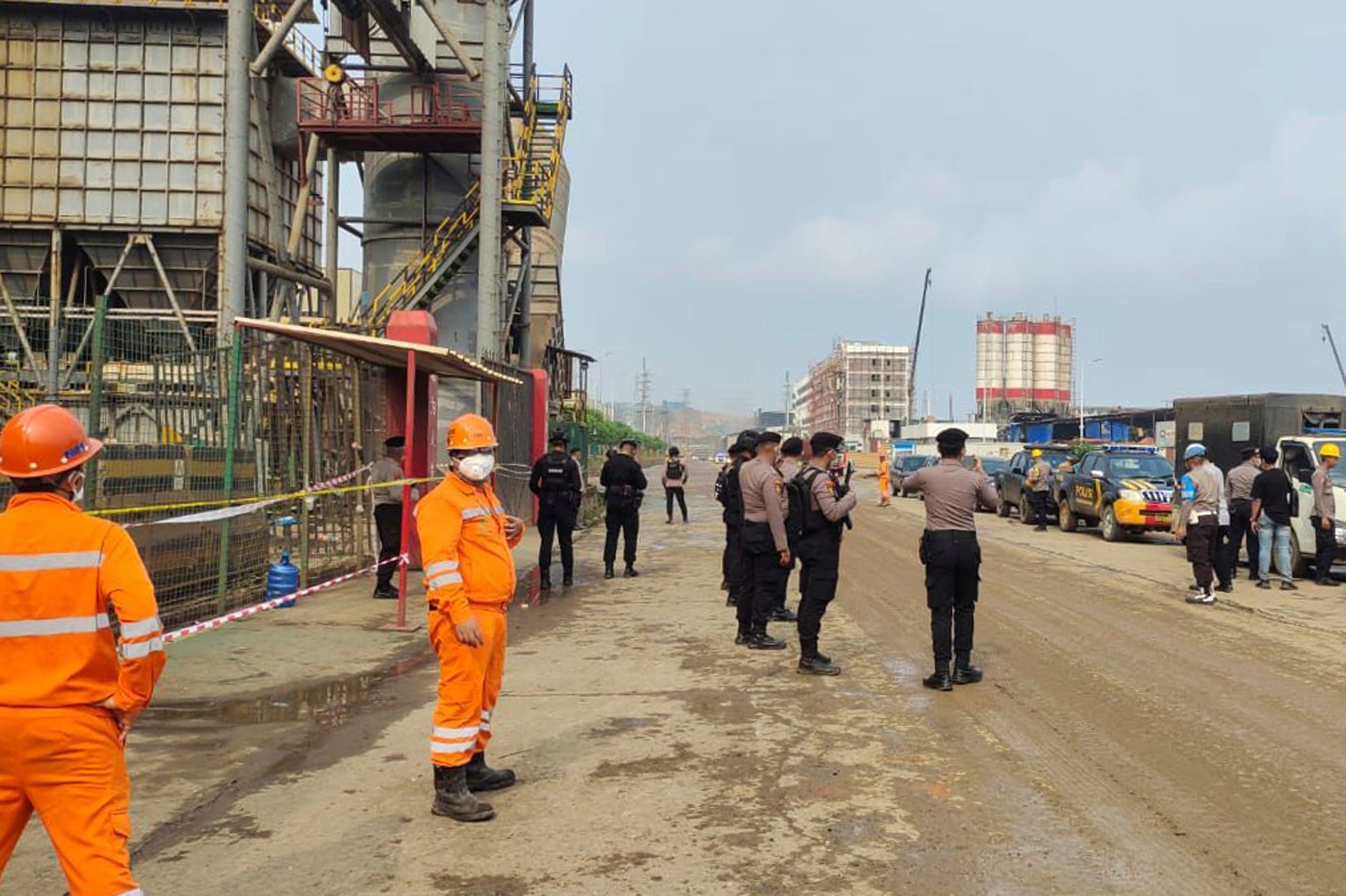 Police officers and workers stand near the site where a furnace explosion occurred at PT Indonesia Tsingshan Stainless Steel smelting plant in Morowali, Central Sulawesi