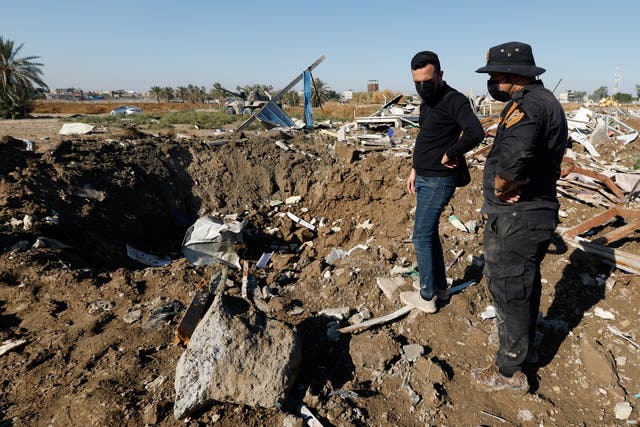 <p>A fighter of the Iraqi Kataib Hezbollah militia group and a man inspect the site of a US airstrike, in Hilla, Iraq on 26 December. </p>