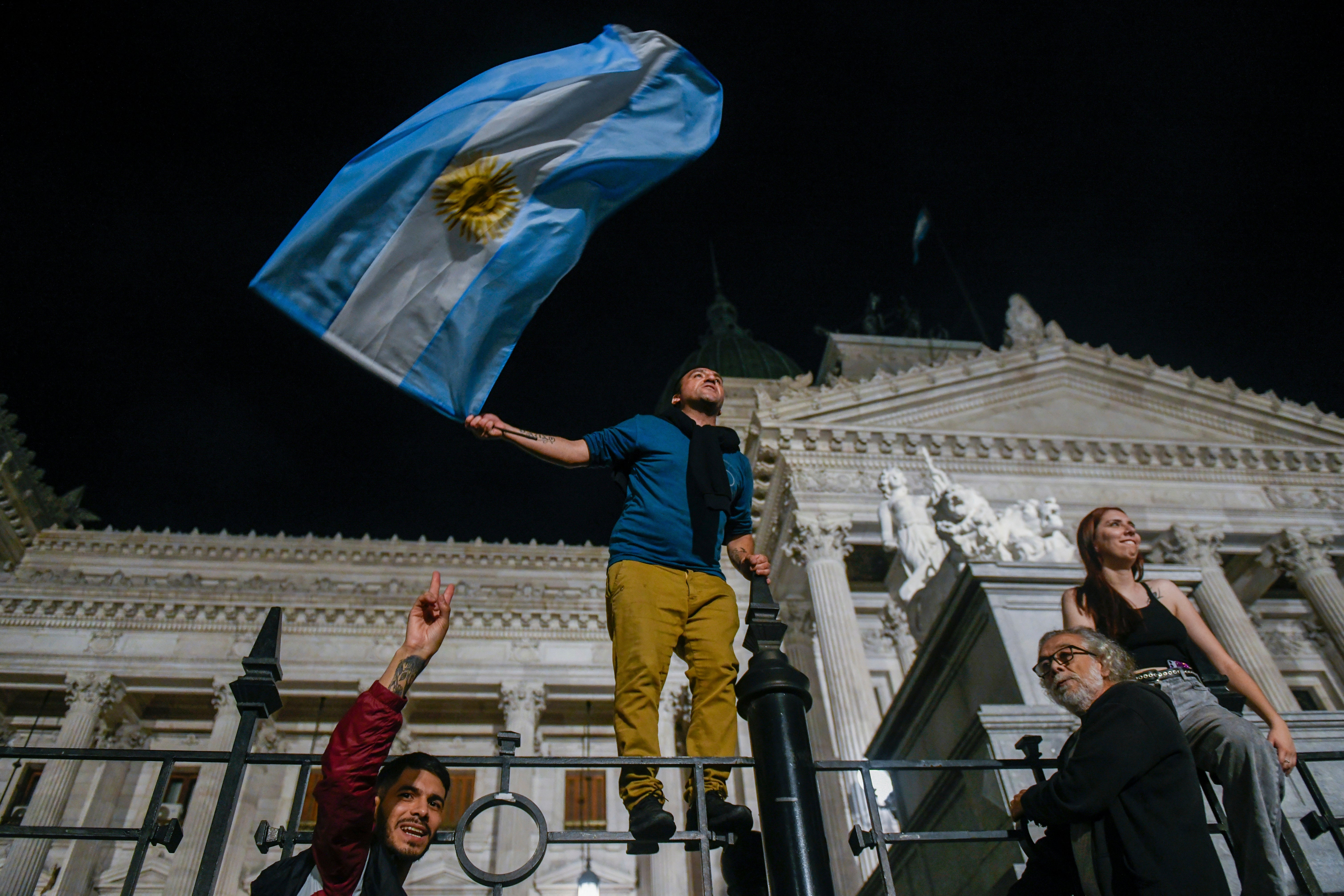 Demonstrators climb to the fence of Congress during protests against economic measures announced by the new president