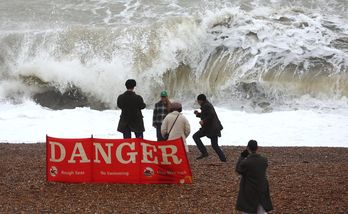Предупреждение за опасно за живота време, тъй като разхождащи се виждат да снимат вълни зад огромен указателен знак