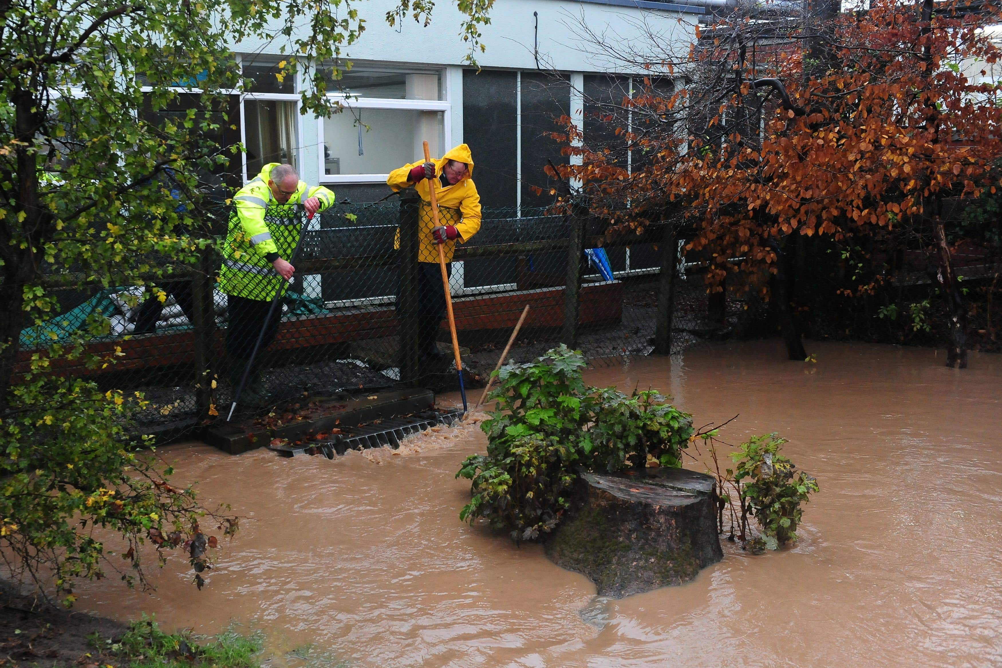 Two men work to keep clear a drain in a beck behind the Friarage Hospital in Northallerton, North Yorkshire, during heavy rains (Anna Gowthorpe/PA)