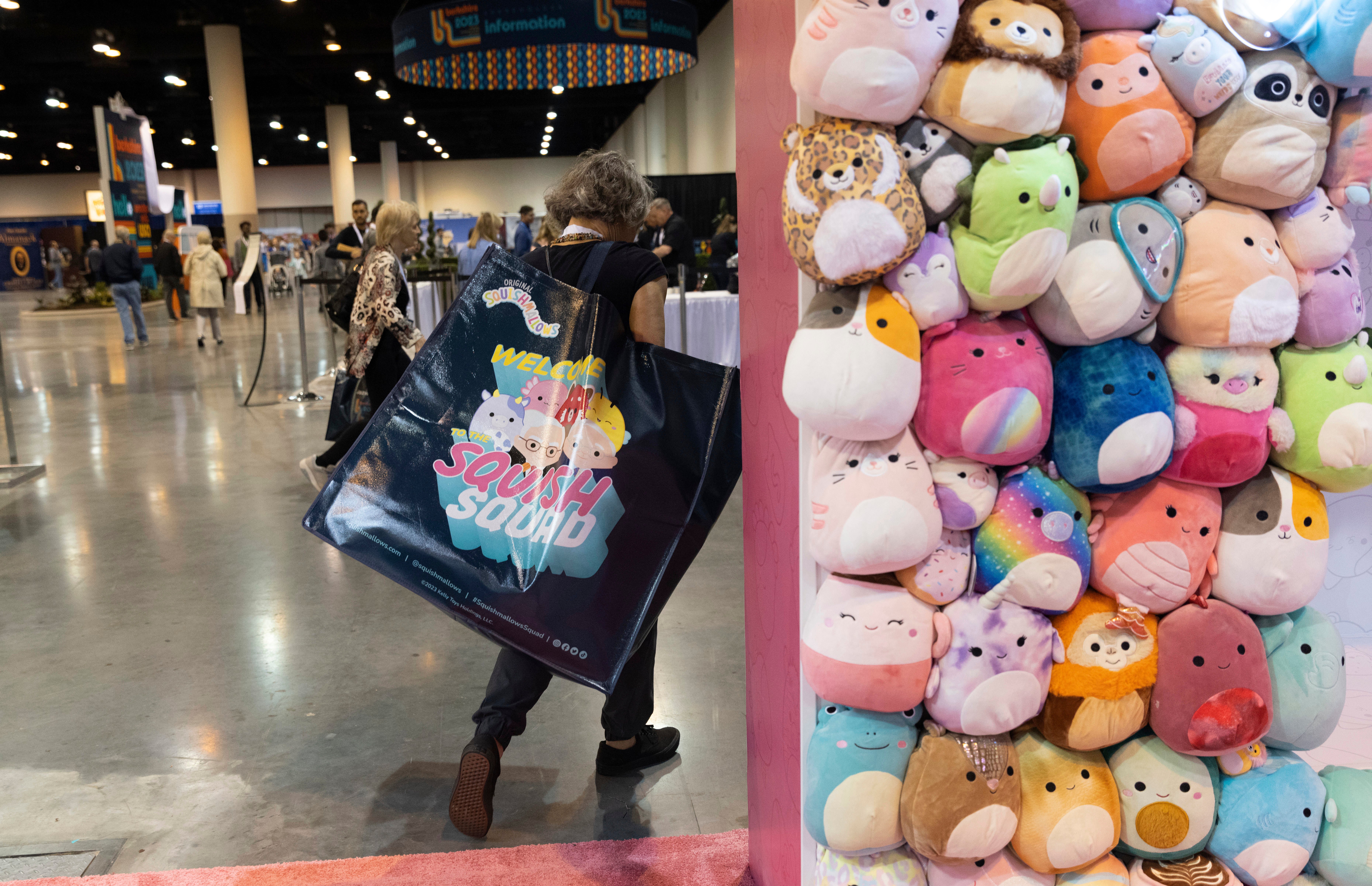 A shareholder leaves the Squishmallows booth with a large bag of purchases in the exhibition hall
