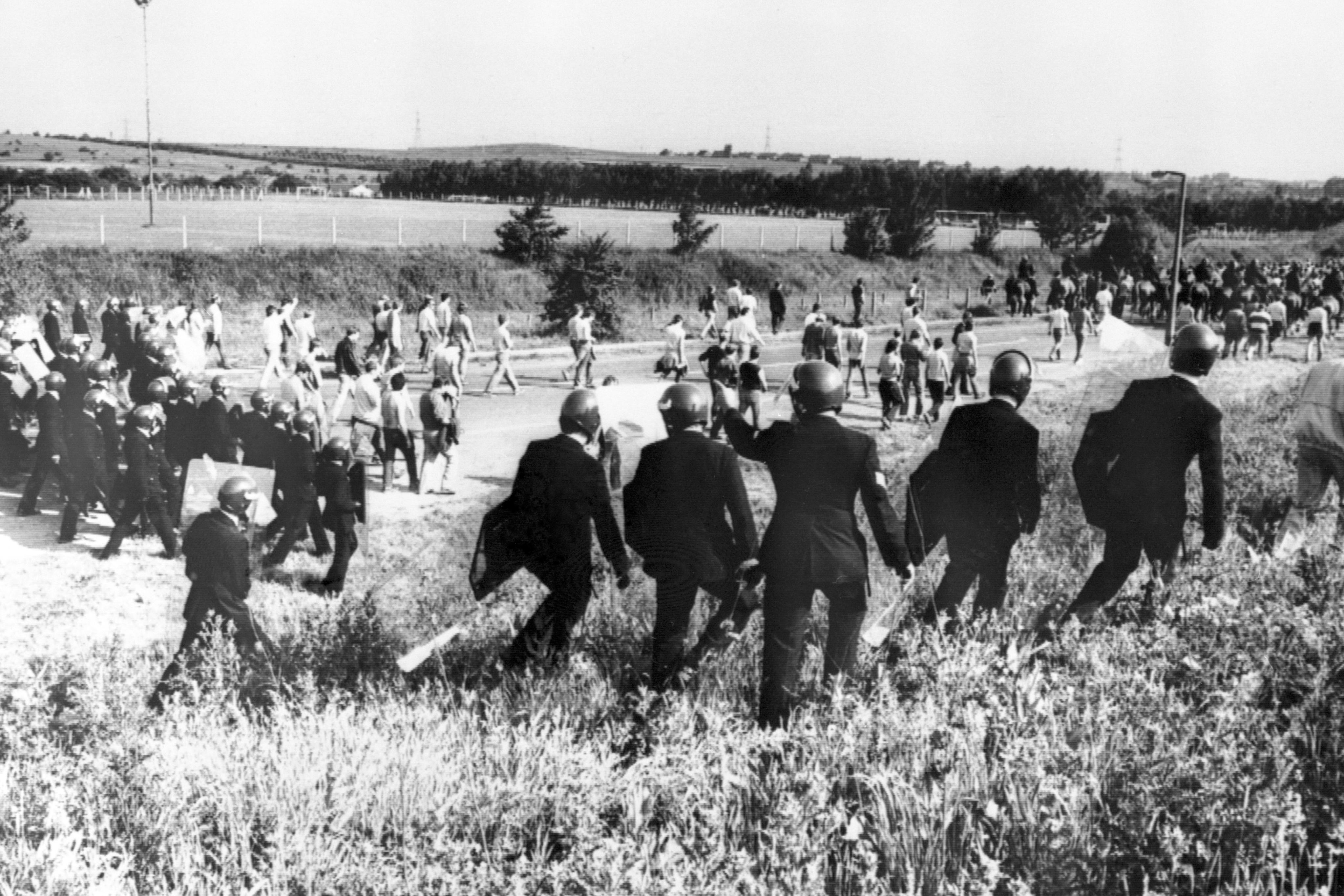 Police in anti-riot gear escort picketers away from their position near the Orgreave coking plant near Rotherham in 1984 (PA)