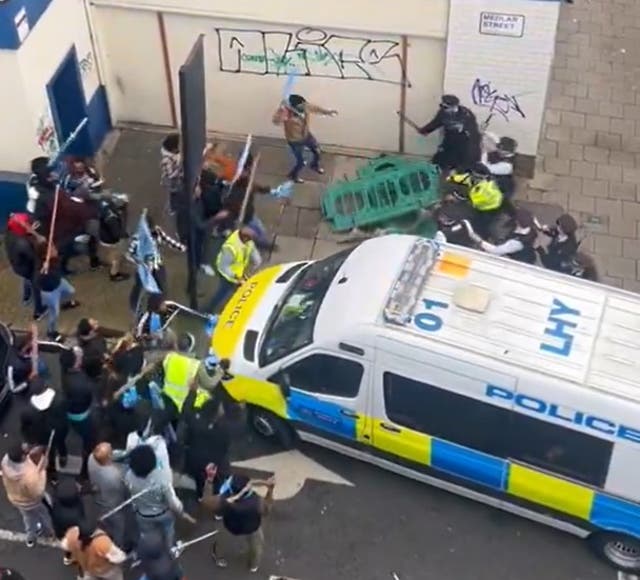 <p>A barrier appears to be thrown at police officers by members of the public involved in the protest</p>