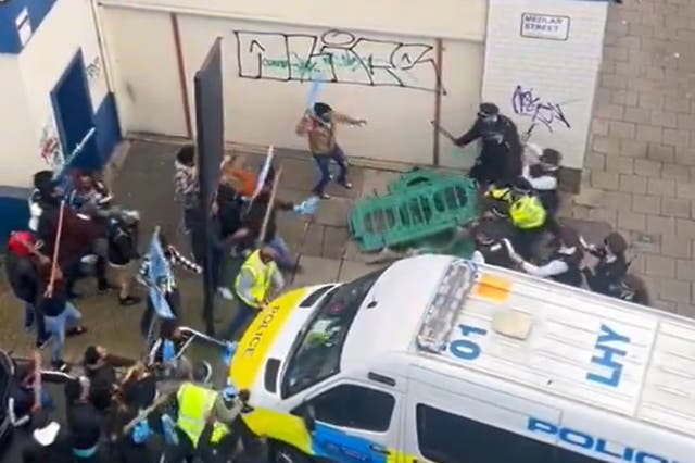 <p>A barrier appears to be thrown at police officers by members of the public involved in the protest</p>