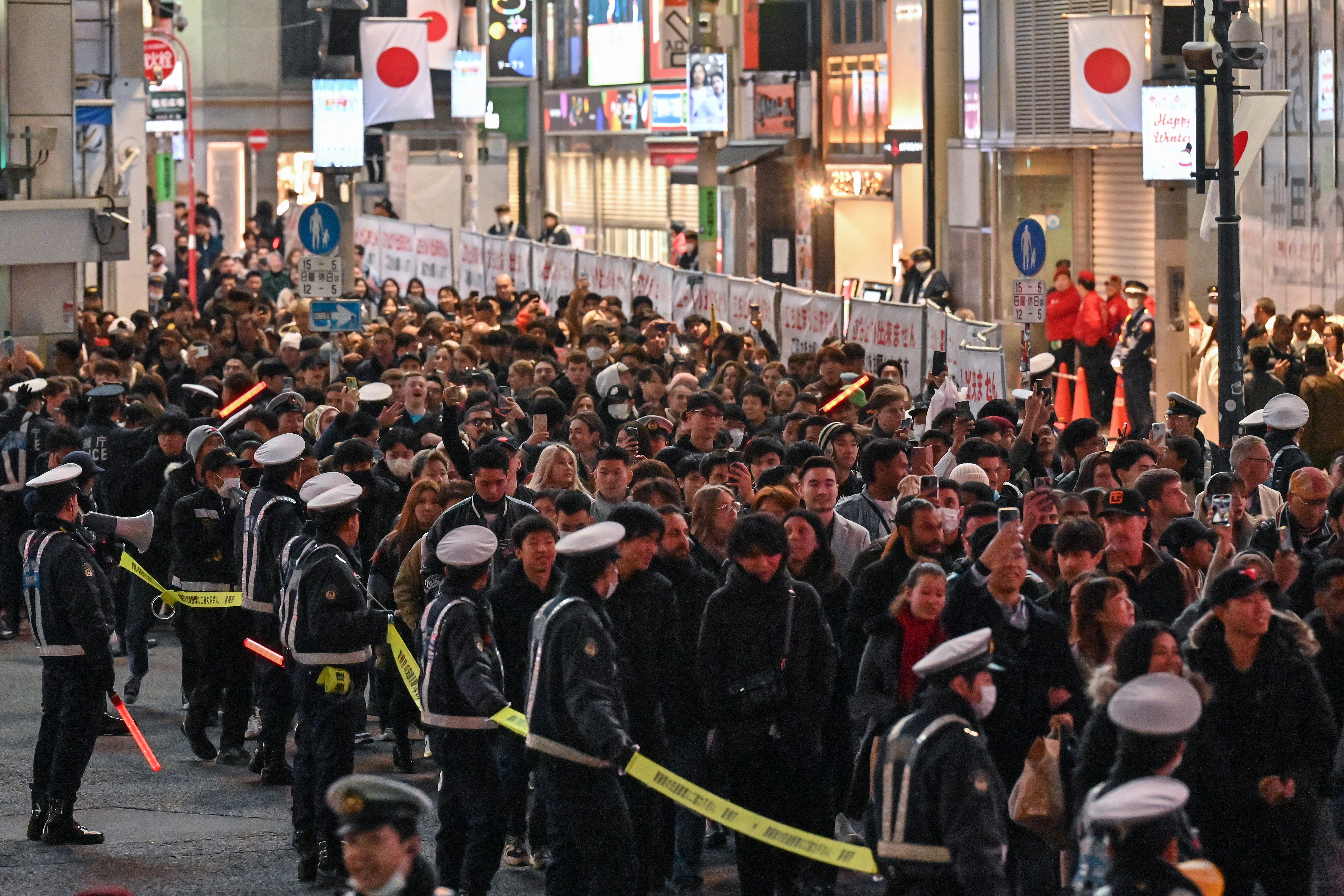 Police cordon pedestrians while they cross Shibuya Crossing in Tokyo on New Year’s Eve ahead of midnight