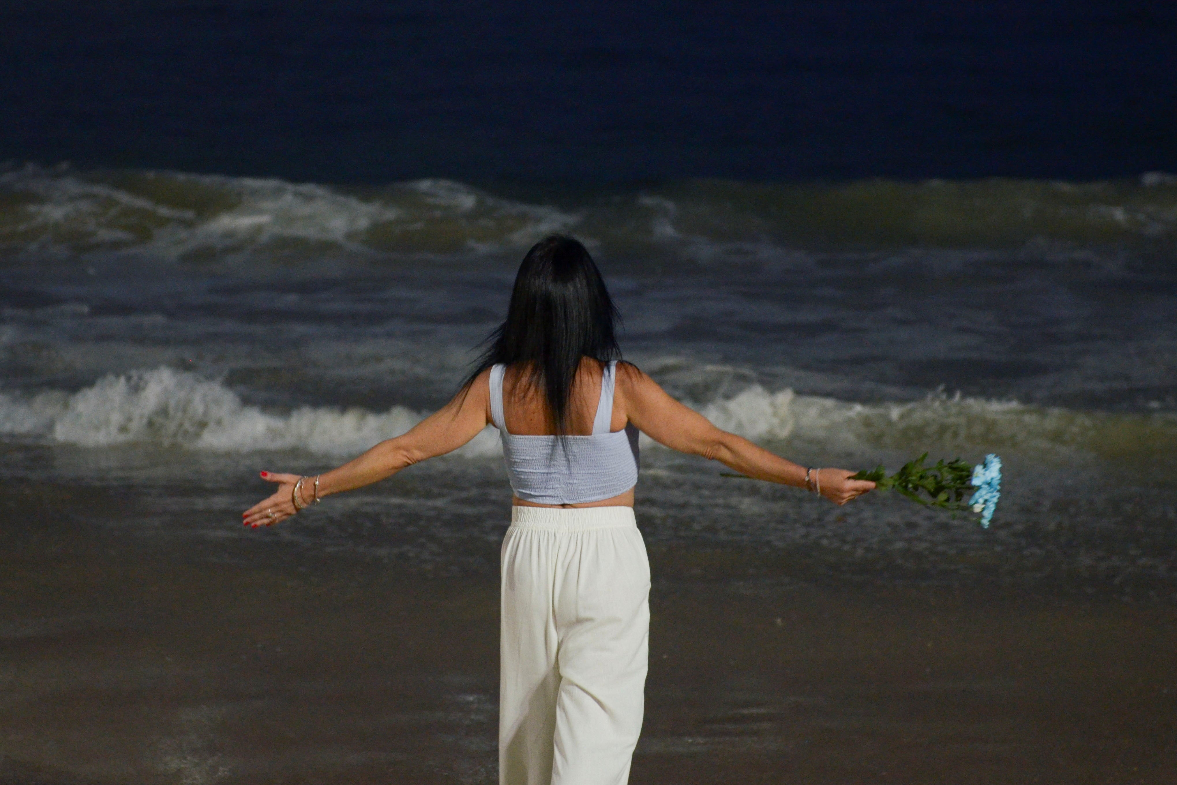 A woman gestures at Copacabana beach while celebrating the New Year, in Rio de Janeiro