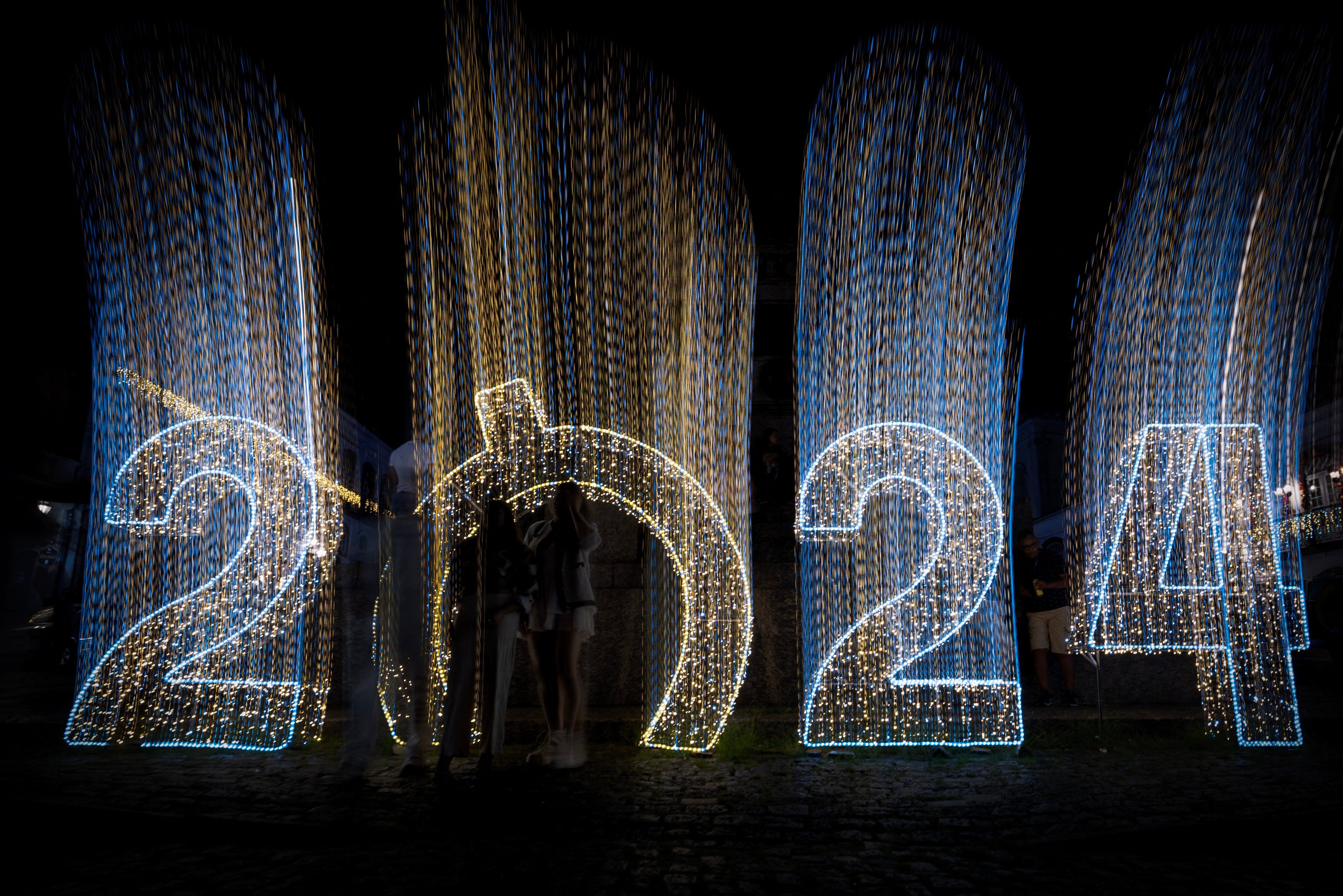 People pose for a picture next to a sign celebrating the upcoming new year in Ouro Preto, Minas Gerais state, Brazil