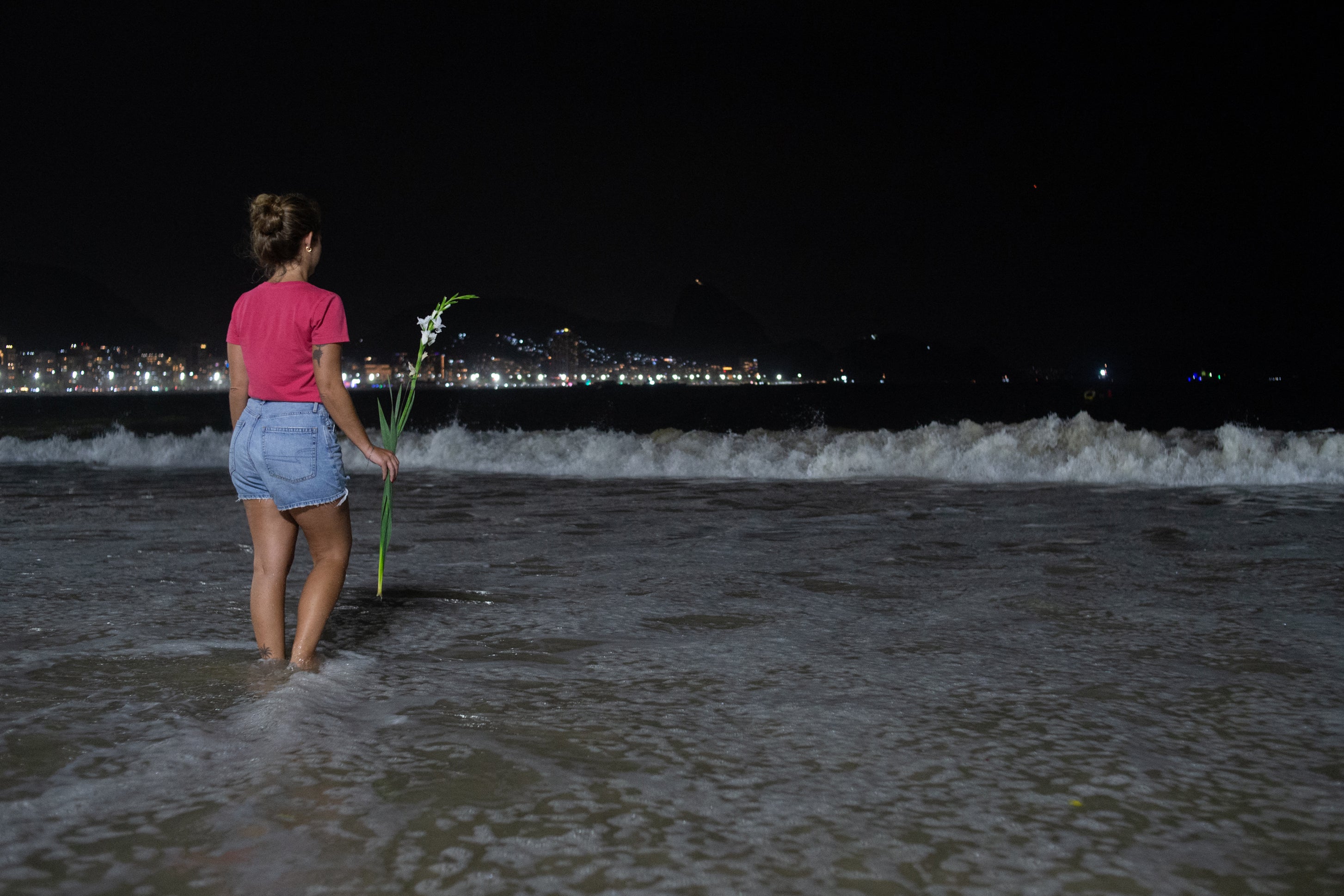 A woman holds flowers on Copacabana Beach in Rio de Janeiro, Brazil, on New Year’s Eve, 31 December 2023