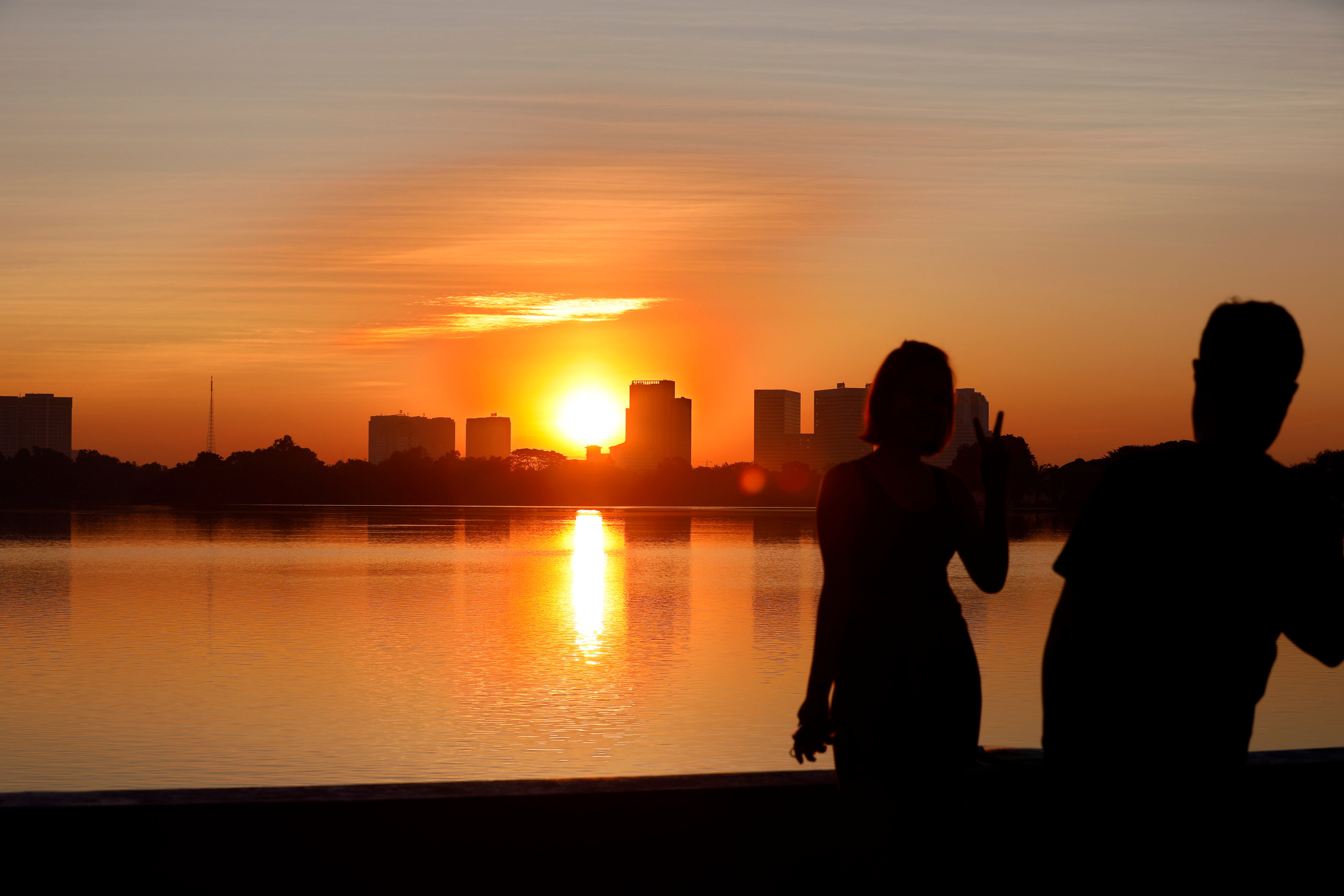 The sun rises on New Years Day as people take photos with their mobile phone over the skyline of Yangon, Myanmar, 1 January 2024