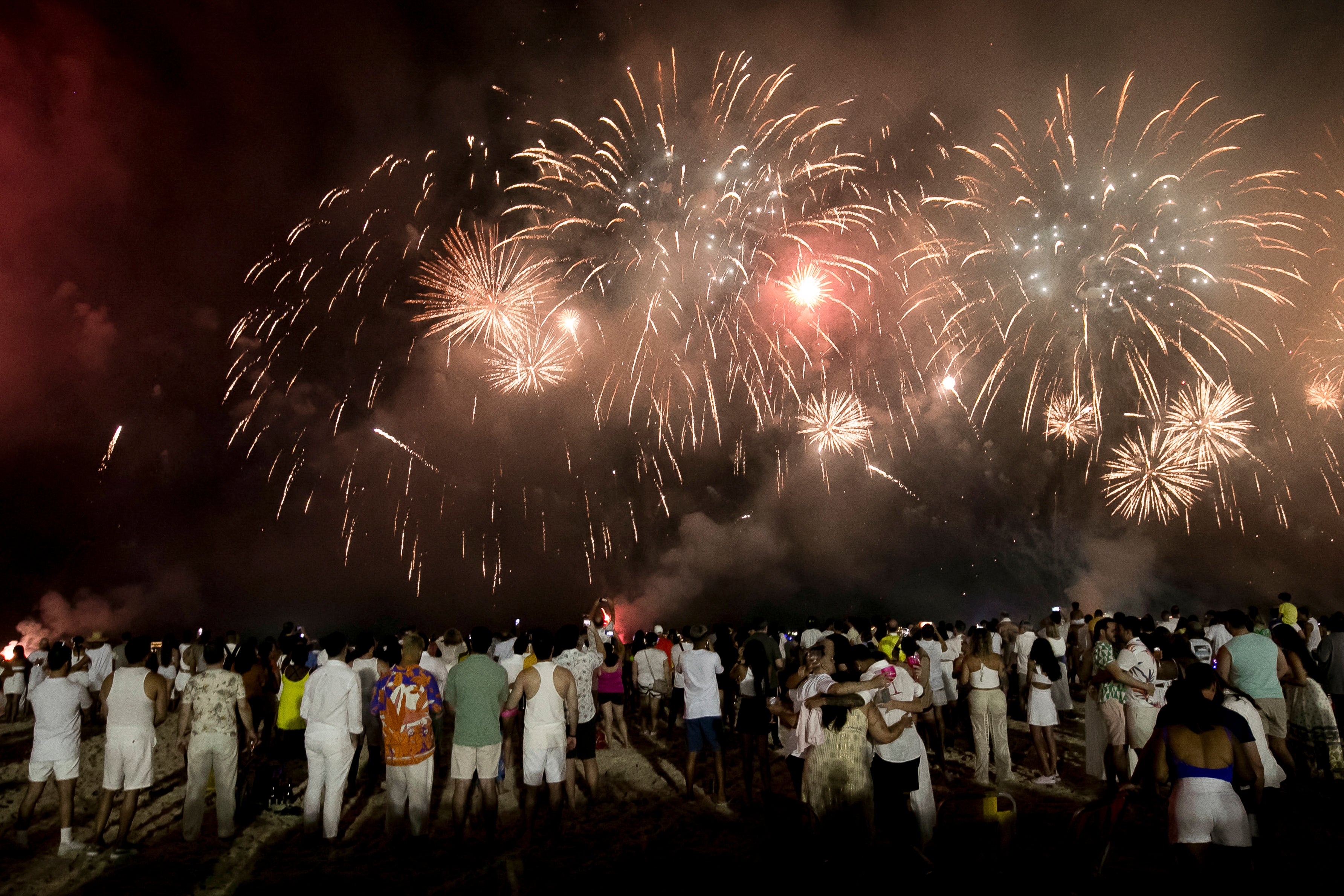 People celebrate the start of the New Year as fireworks illuminate Copacabana Beach in Rio de Janeiro, Brazil, early Monday, 1 January 2024