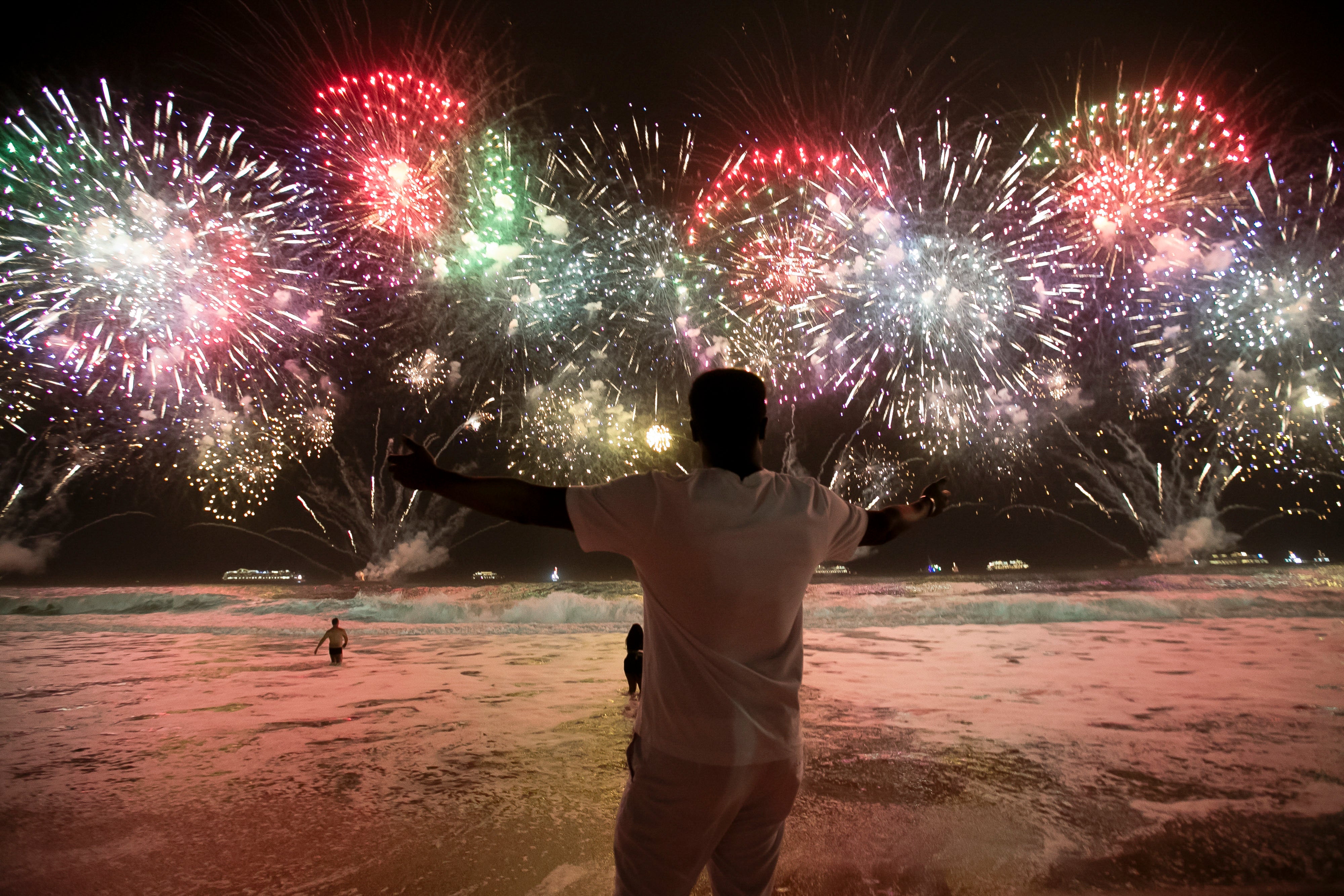 A man celebrates the start of the New Year as fireworks illuminate Copacabana Beach in Rio de Janeiro, Brazil, early Monday, 1 January 2024