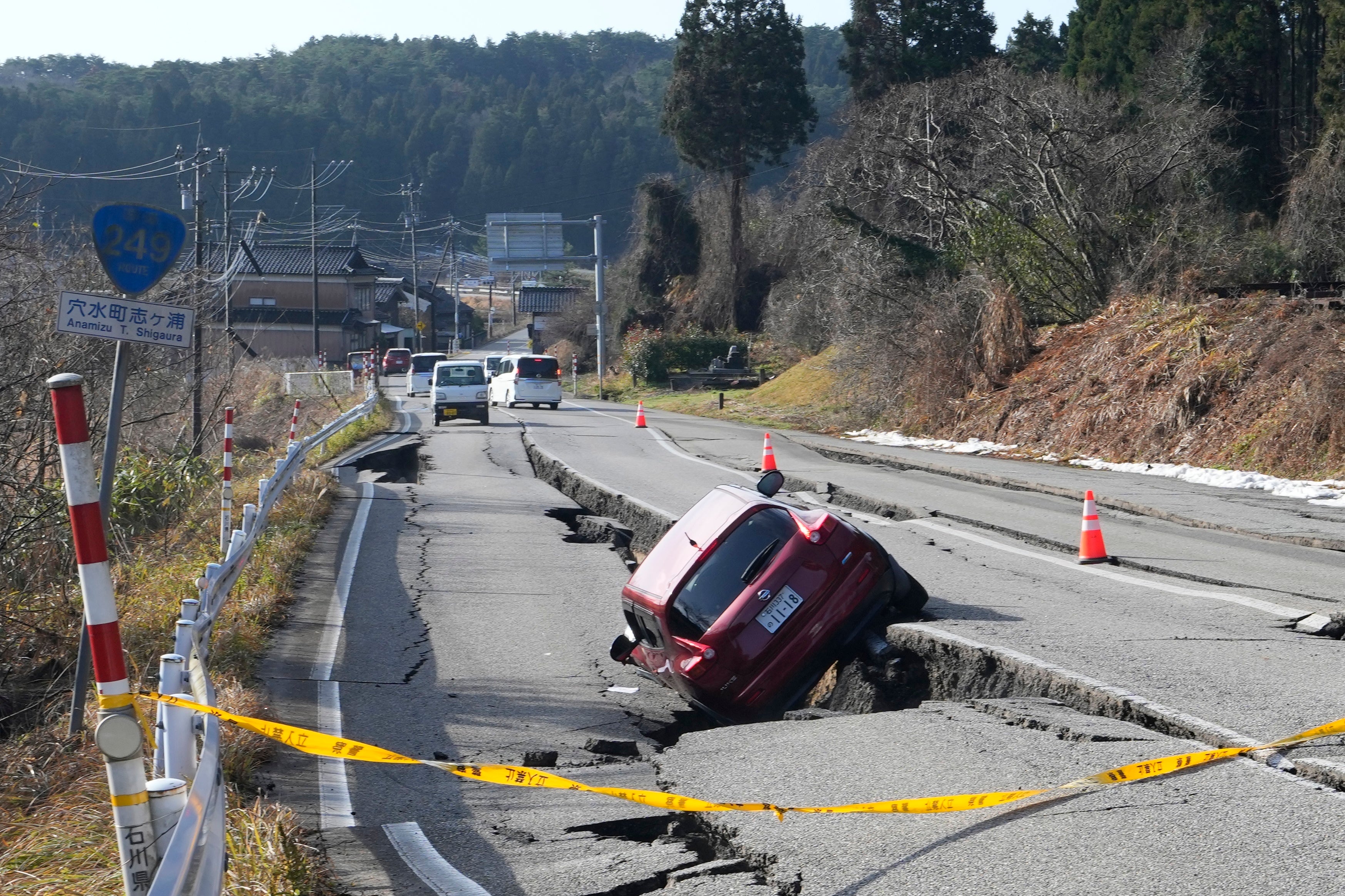 A car is trapped at a partially collapsed road caused by a powerful earthquake near Anamizu Town