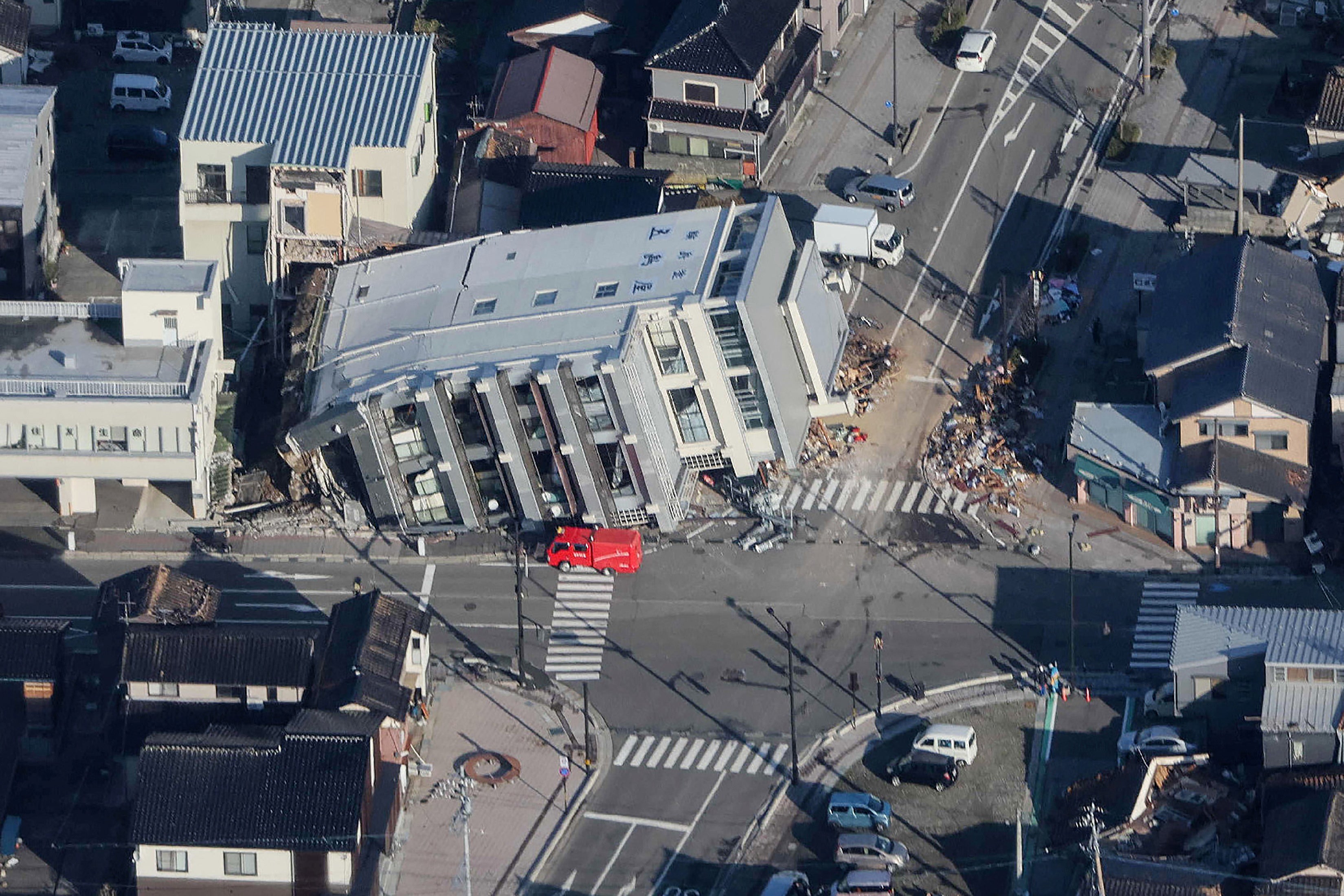 A rescue vehicle (C) parked next to a seven-storey building which fell over in Wajima, Ishikawa prefecture