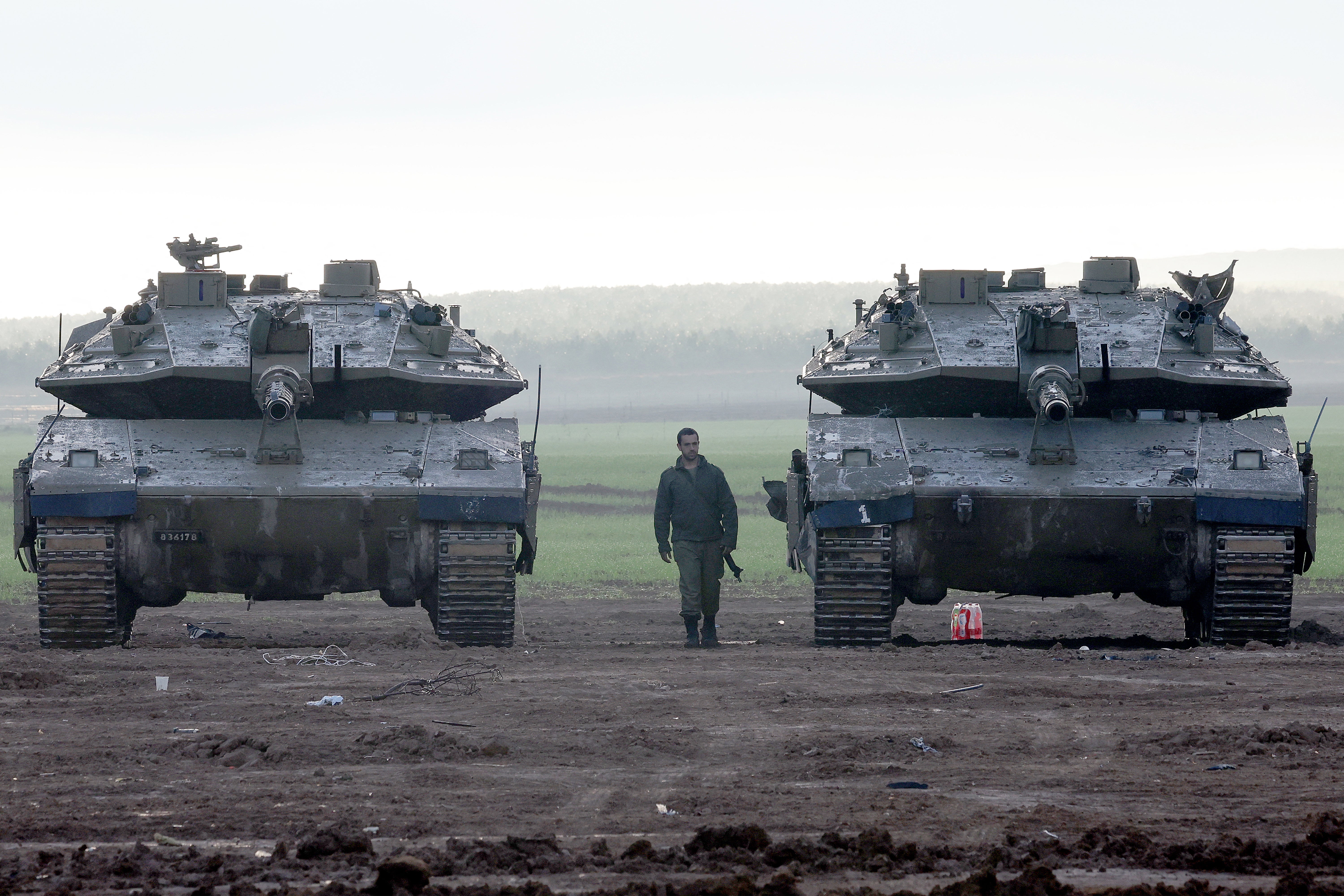 An Israeli soldier walks between two Israeli battle tanks among others deployed at a position along the border with the Gaza Strip and southern Israel on 2 January 2024