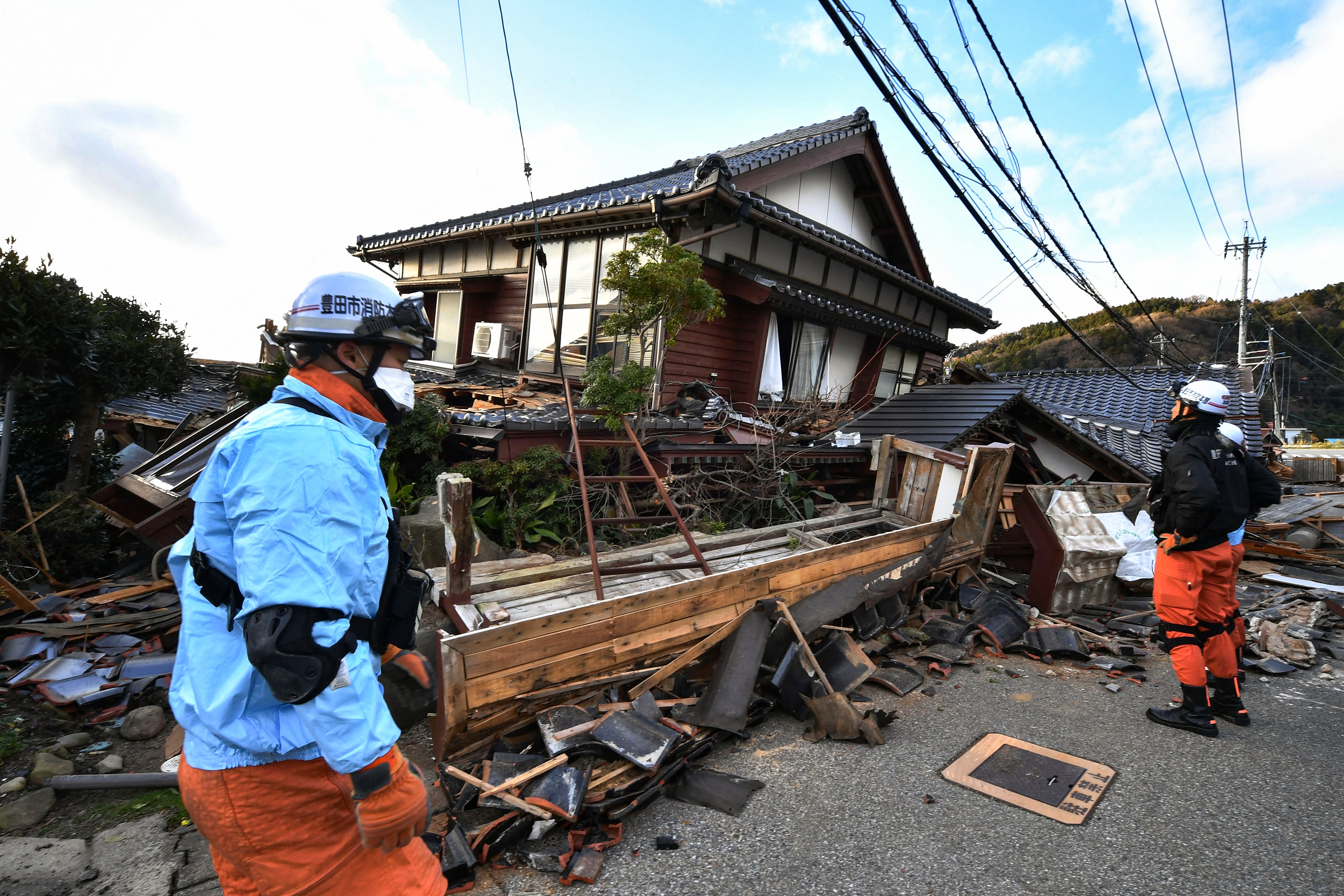 Firefighters inspect collapsed wooden houses in Wajima, Ishikawa prefecture