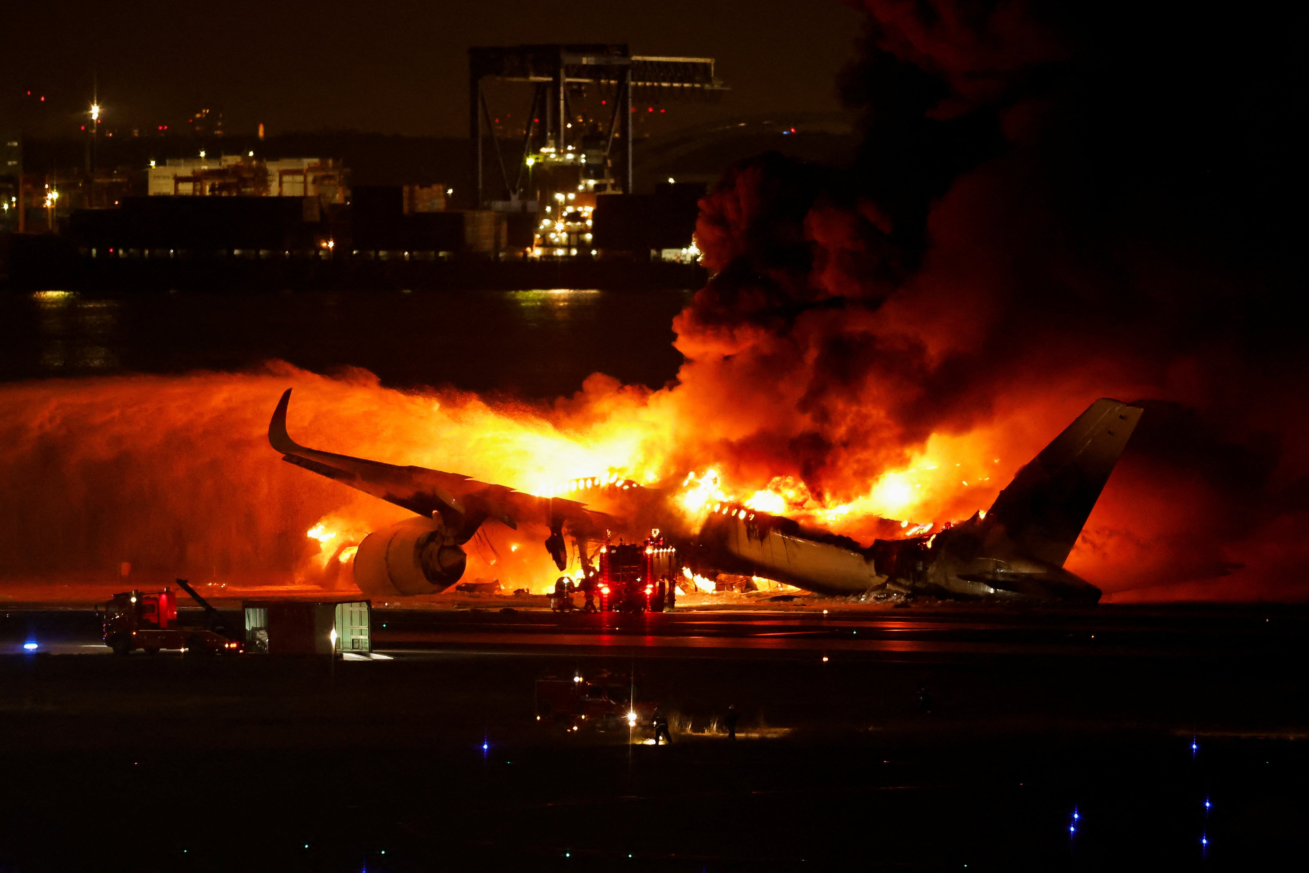 Firefighters work at Haneda International Airport after Japan Airlines' A350 airplane caught on fire