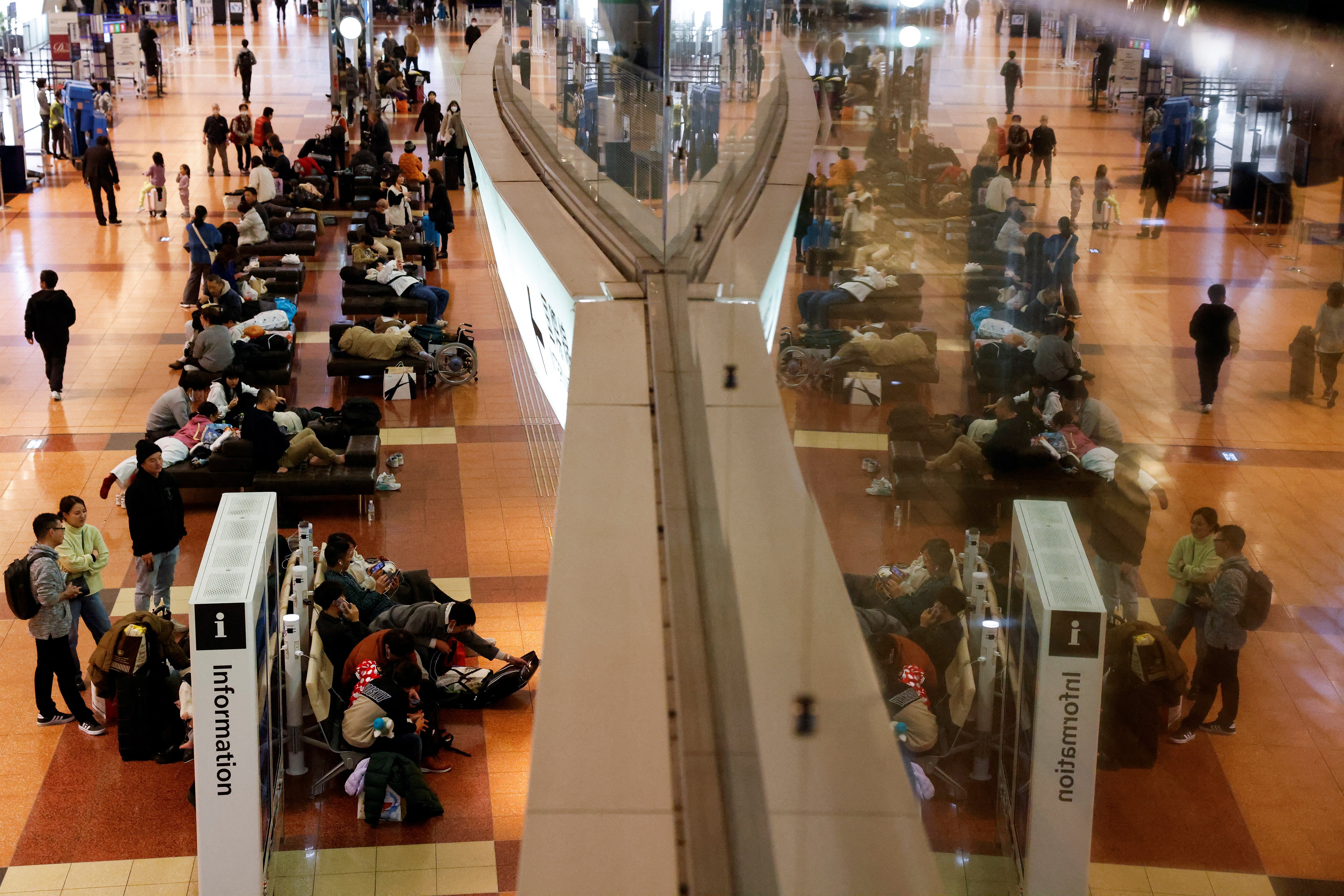 Passengers wait in Terminal 2 of Haneda International Airport, as operations are suspended due to a Japan Airlines' A350 airplane and a Coast Guard aircraft collision