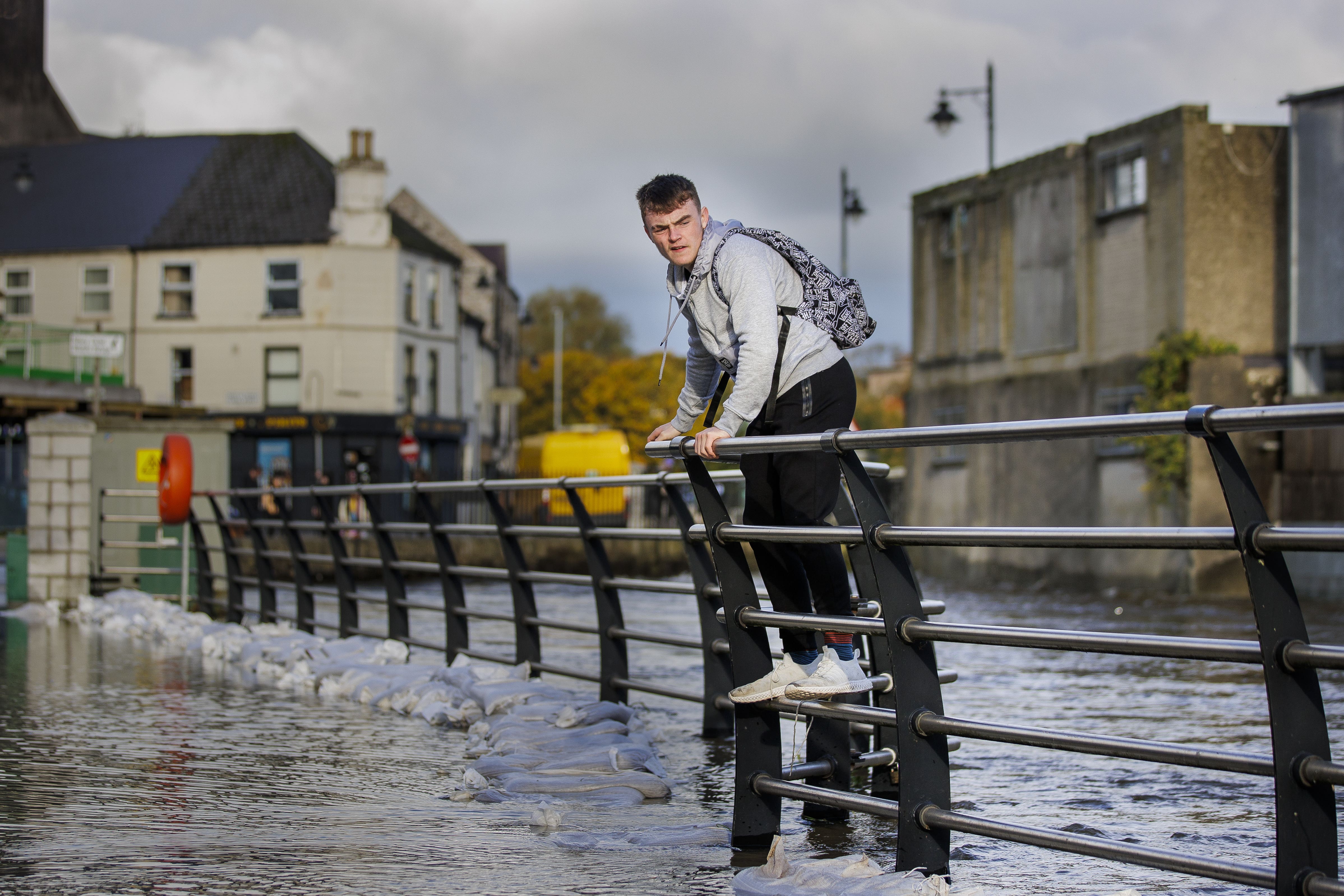 A man walks along a fence to avoid floodwater in Newry, Co Down, in October (Liam McBurney/PA)