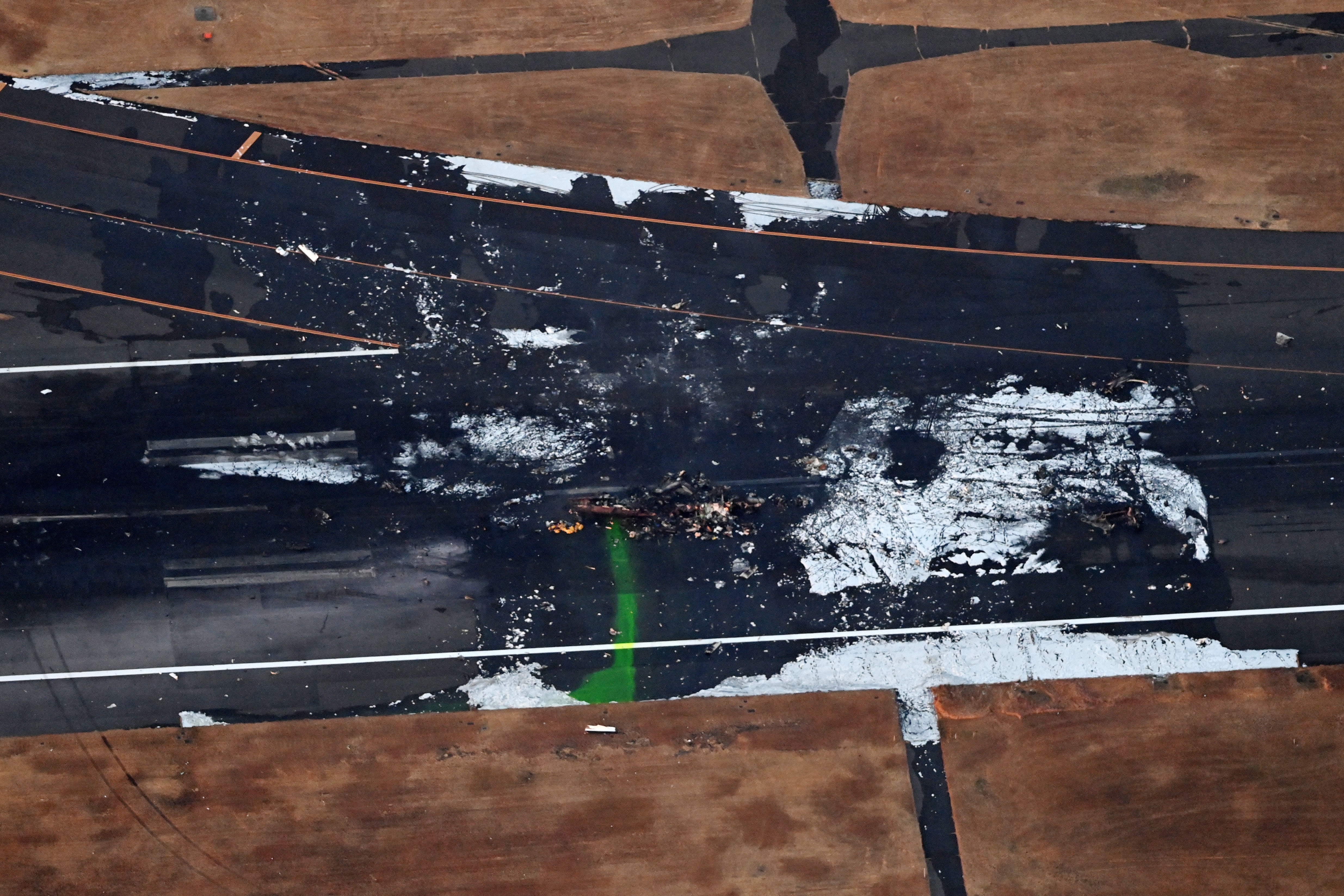 n this aerial image, the debris of MA-722, a Bombardier Dash-8, Japan Coast Guard (JCG) aircraft is seen a day after the collision with a Japan Airlines Flight 516 at Haneda Airport