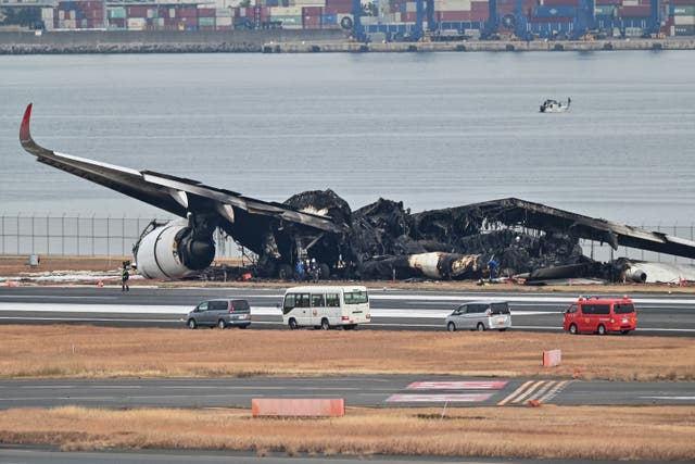 <p>Officials look at the burnt wreckage of a Japan Airlines (JAL) passenger plane on the tarmac at Tokyo International Airport at Haneda in Tokyo</p>