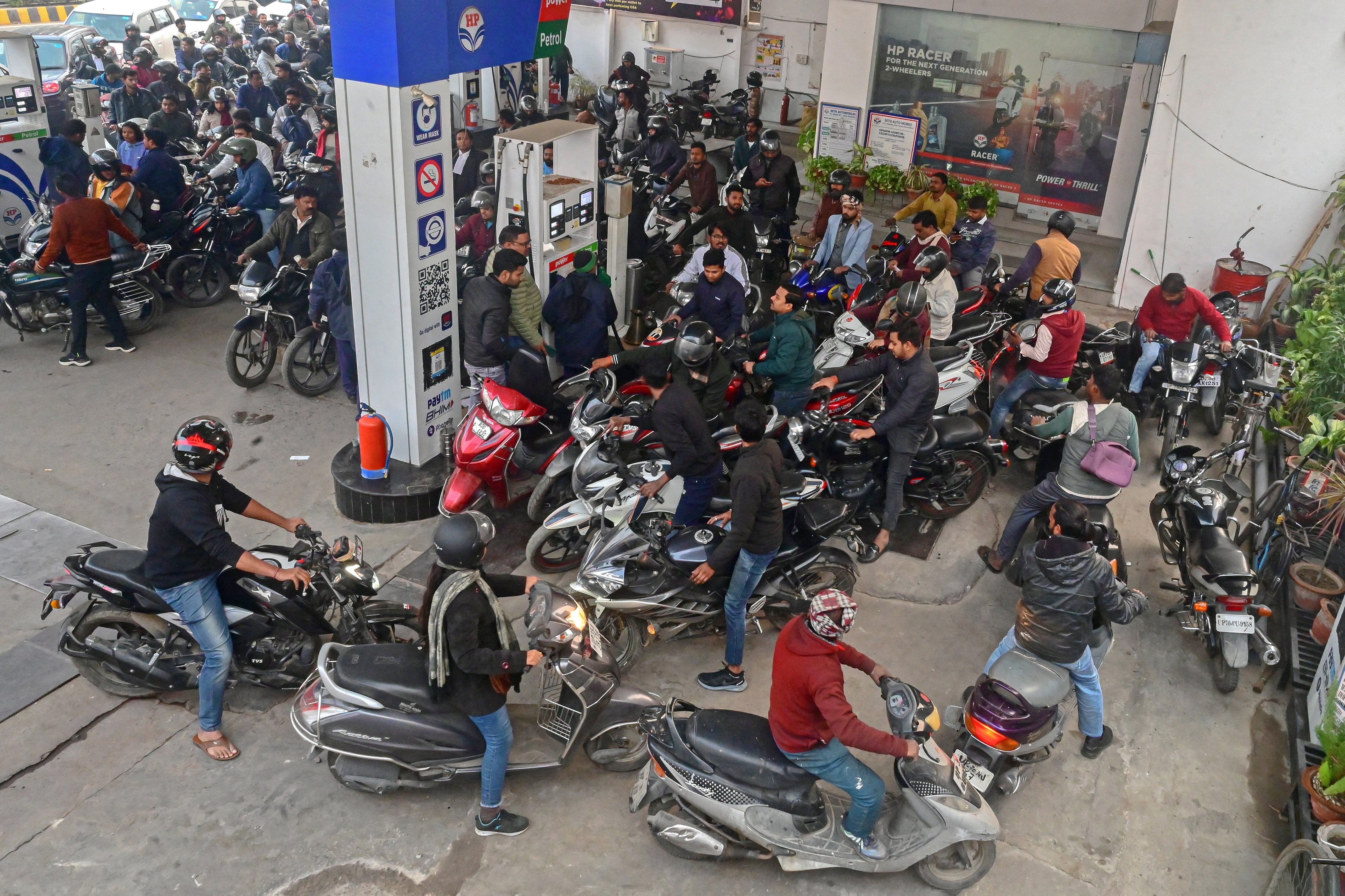 People with their vehicles wait to refill fuel tanks at a fuel station in Prayagraj, Uttar Pradesh