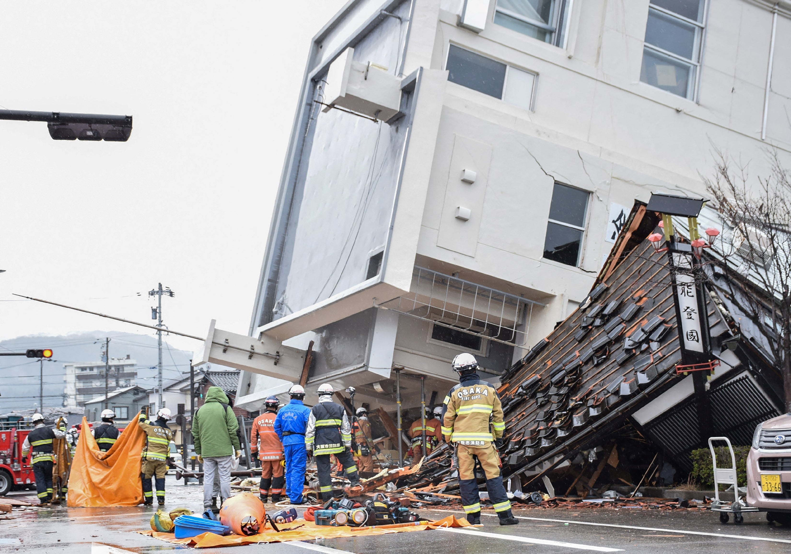 <p>Firefighters work at the scene where a multistorey building toppled over</p>