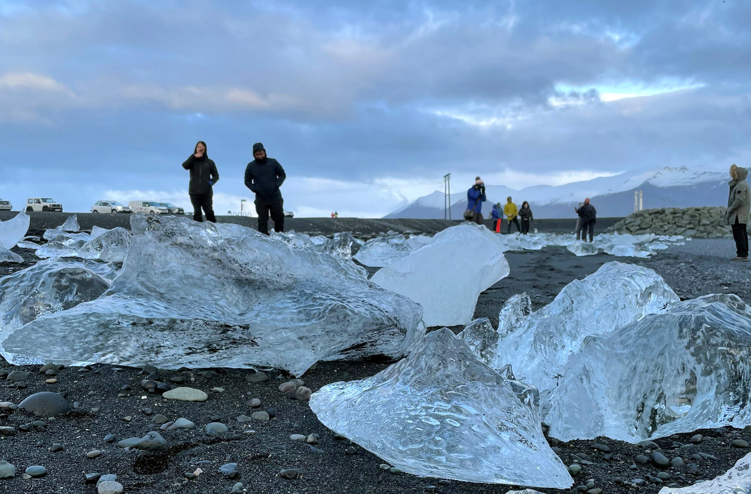 This Nov. 18, 2023 image provided by Beth Harpaz shows visitors amid mini-icebergs on Diamond Beach on Iceland's South Coast
