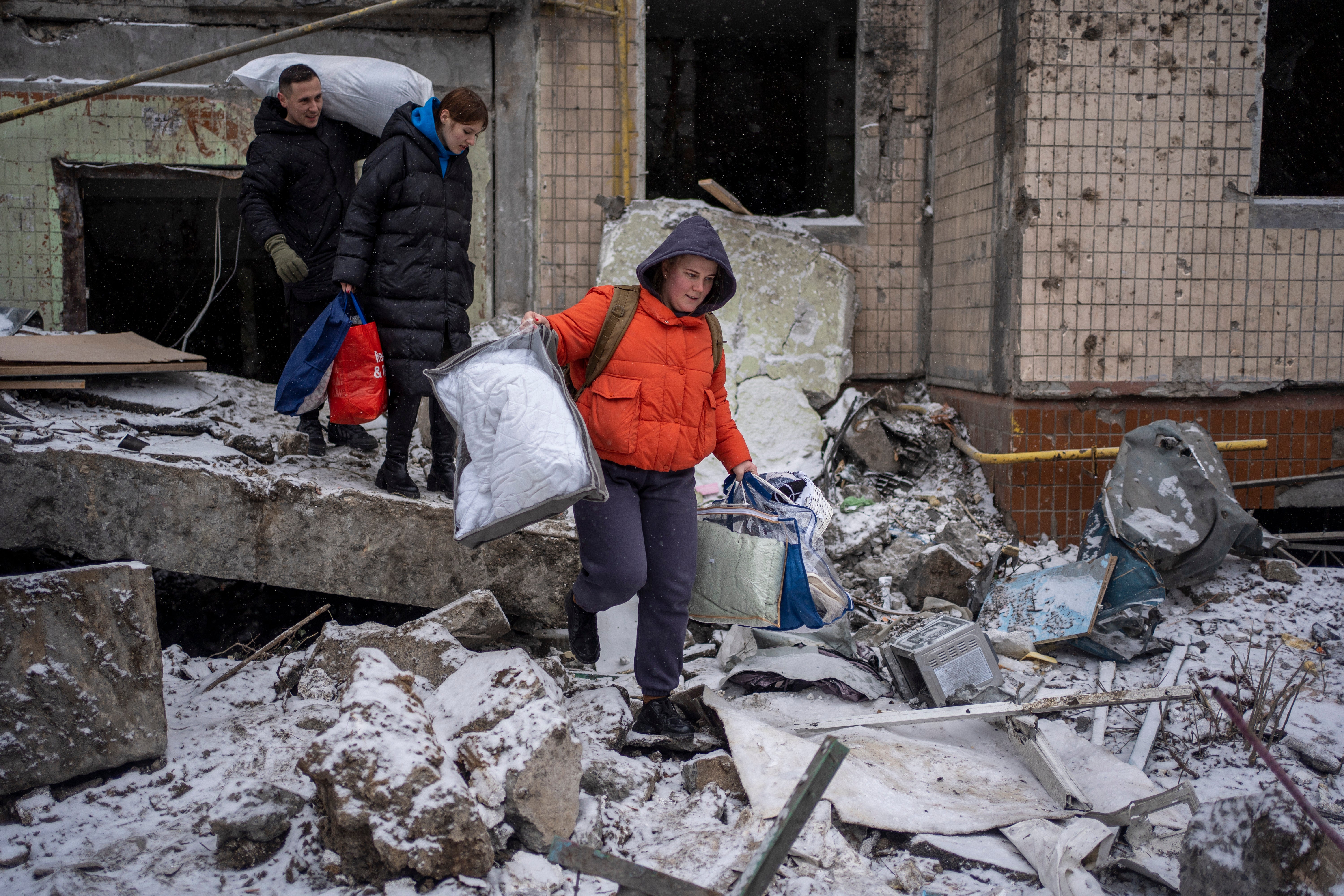 A woman carries belongings rescued from an apartment that was destroyed as a result of Russia’s attack on 2 January