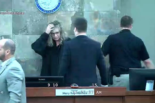 <p>Clark County District Court judge Mary Kay Holthus is seen cradling her head after a defendant launched over her desk during his sentencing in felony battery case</p>
