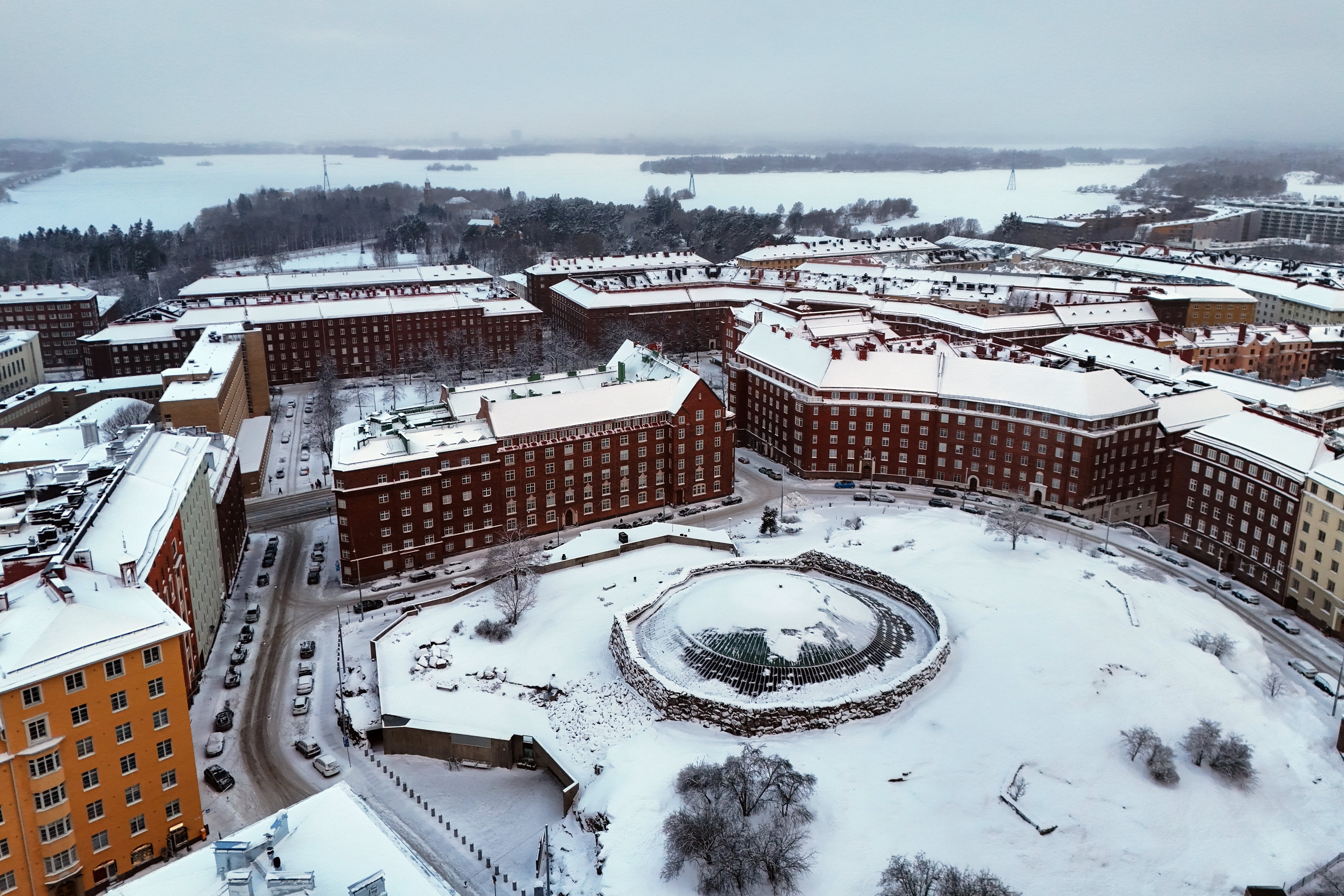 An aerial view taken on January 3, 2024 shows snow and ice in the T????l?? area with the Temppeliaukio Church (front C) and Lapinlahti Bay in the Finnish capital Helsinki