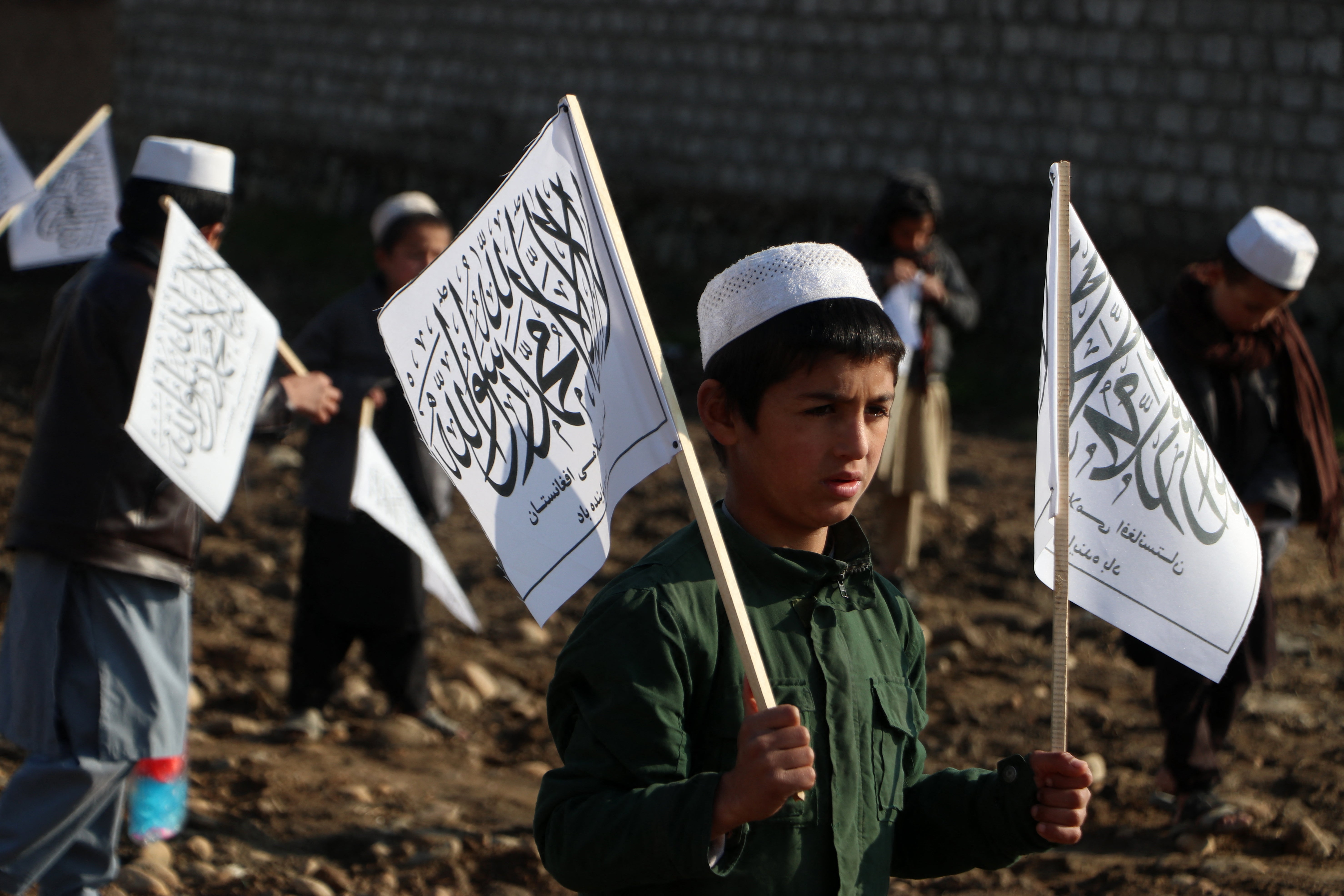 Afghan children from a madrassa or an Islamic school hold Taliban’s flag in Fayzabad district of Badakhshan province
